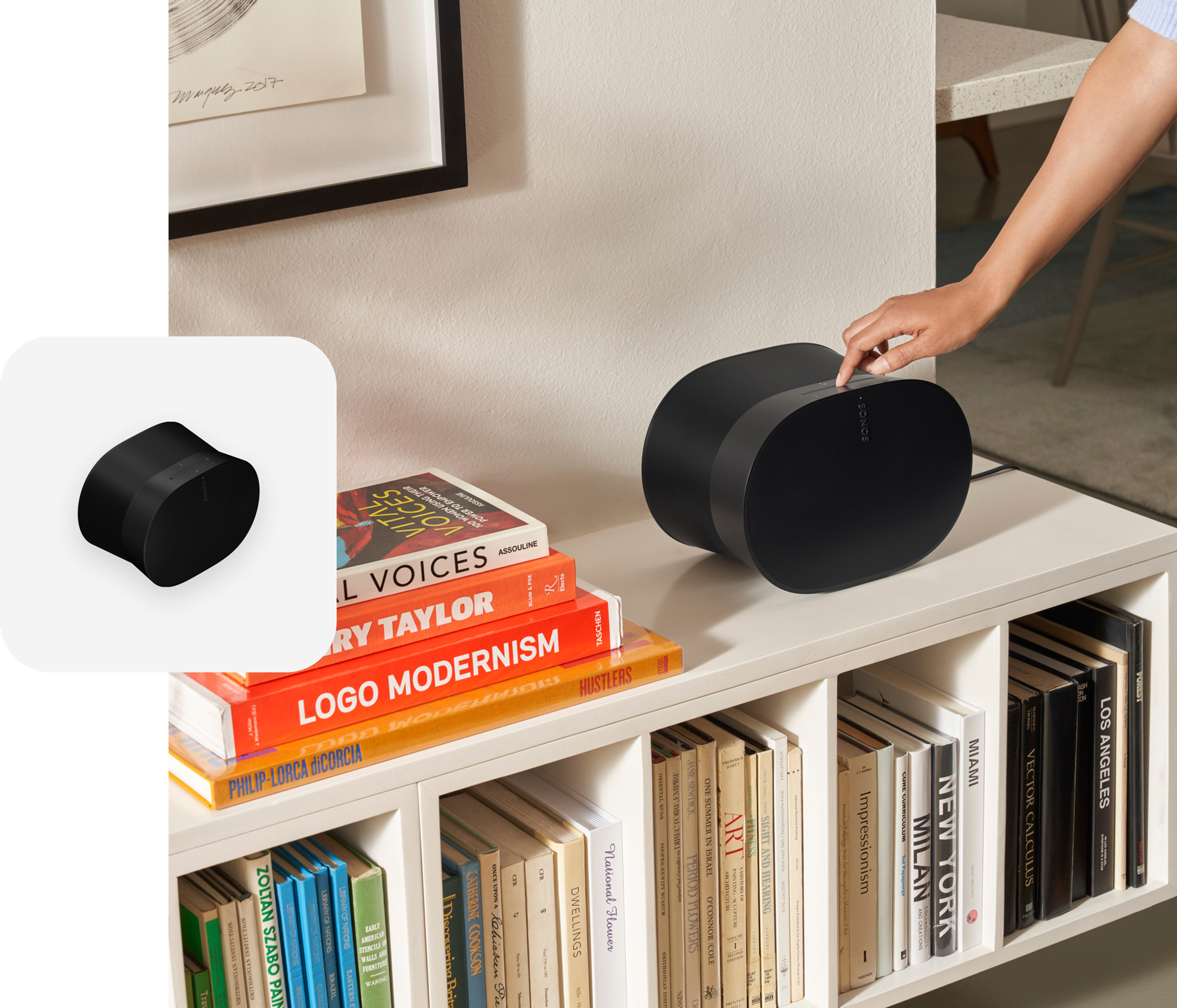 User engaging with the touch controls on a black Era 300 speaker on a white media console