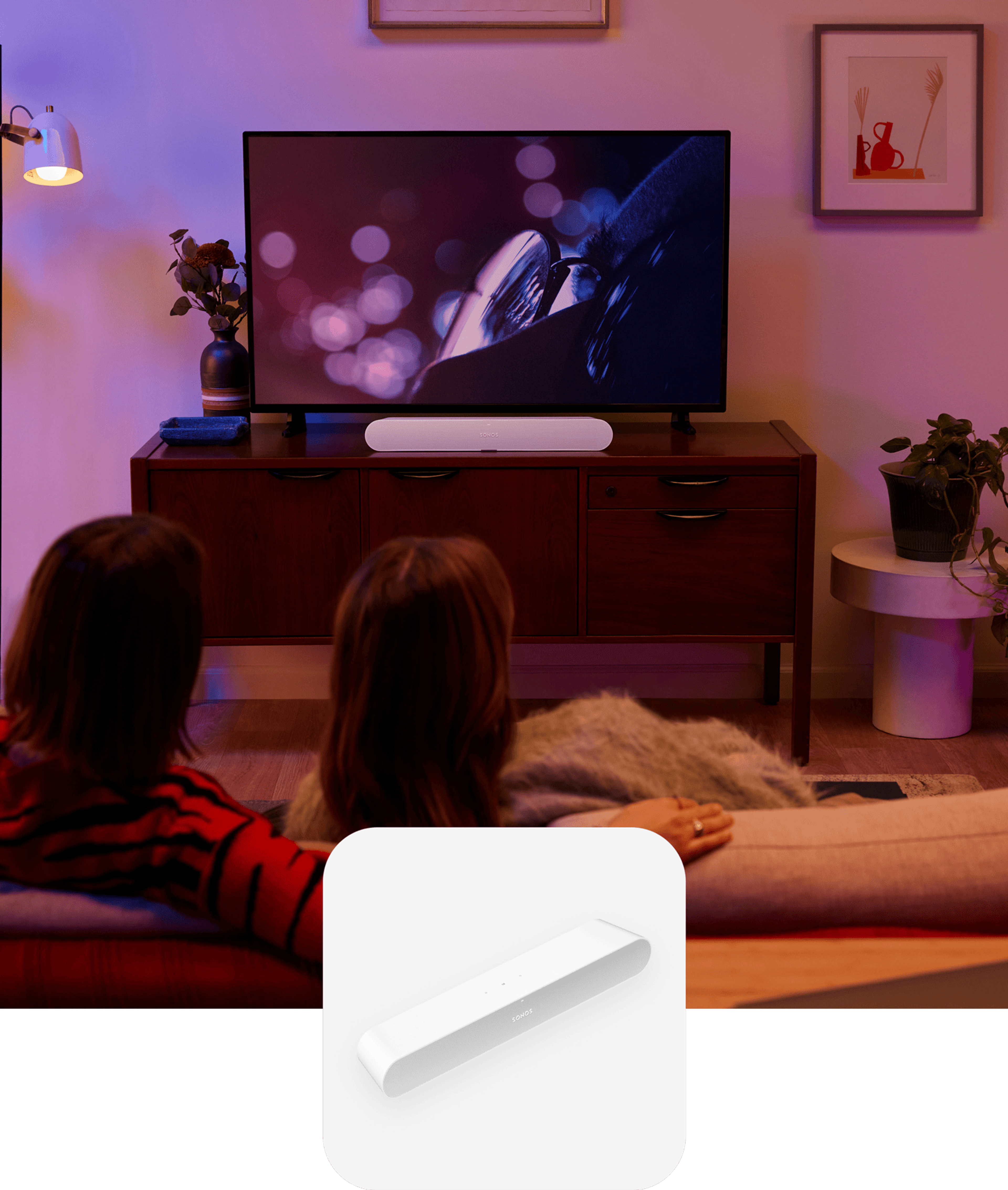 Couple on the couch in their living room watching a film with sound from a white Sonos Ray soundbar