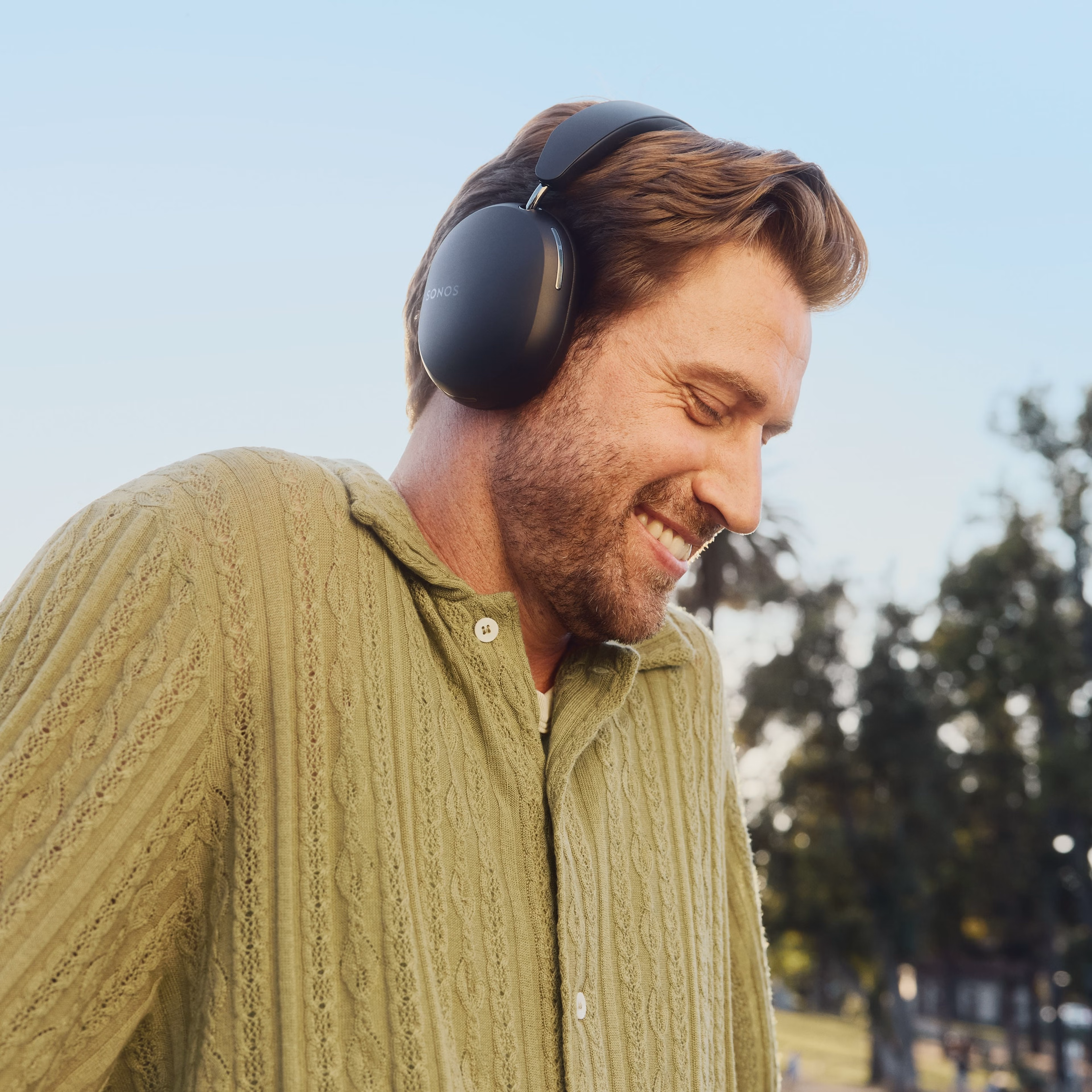 Side profile of female user wearing a pair of black Sonos Ace headphones