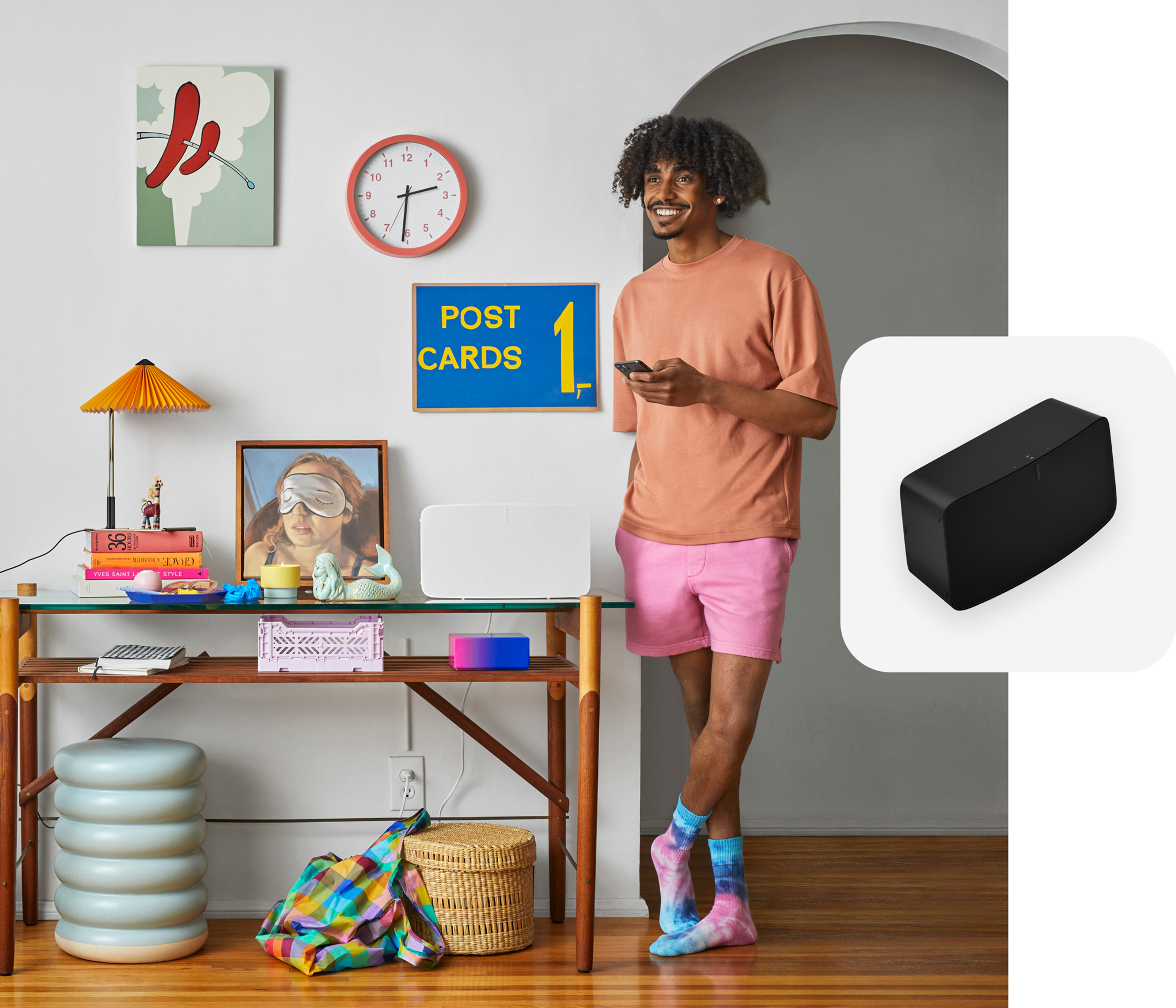 User standing next to his white Sonos Five speaker controlling it with the Sonos app