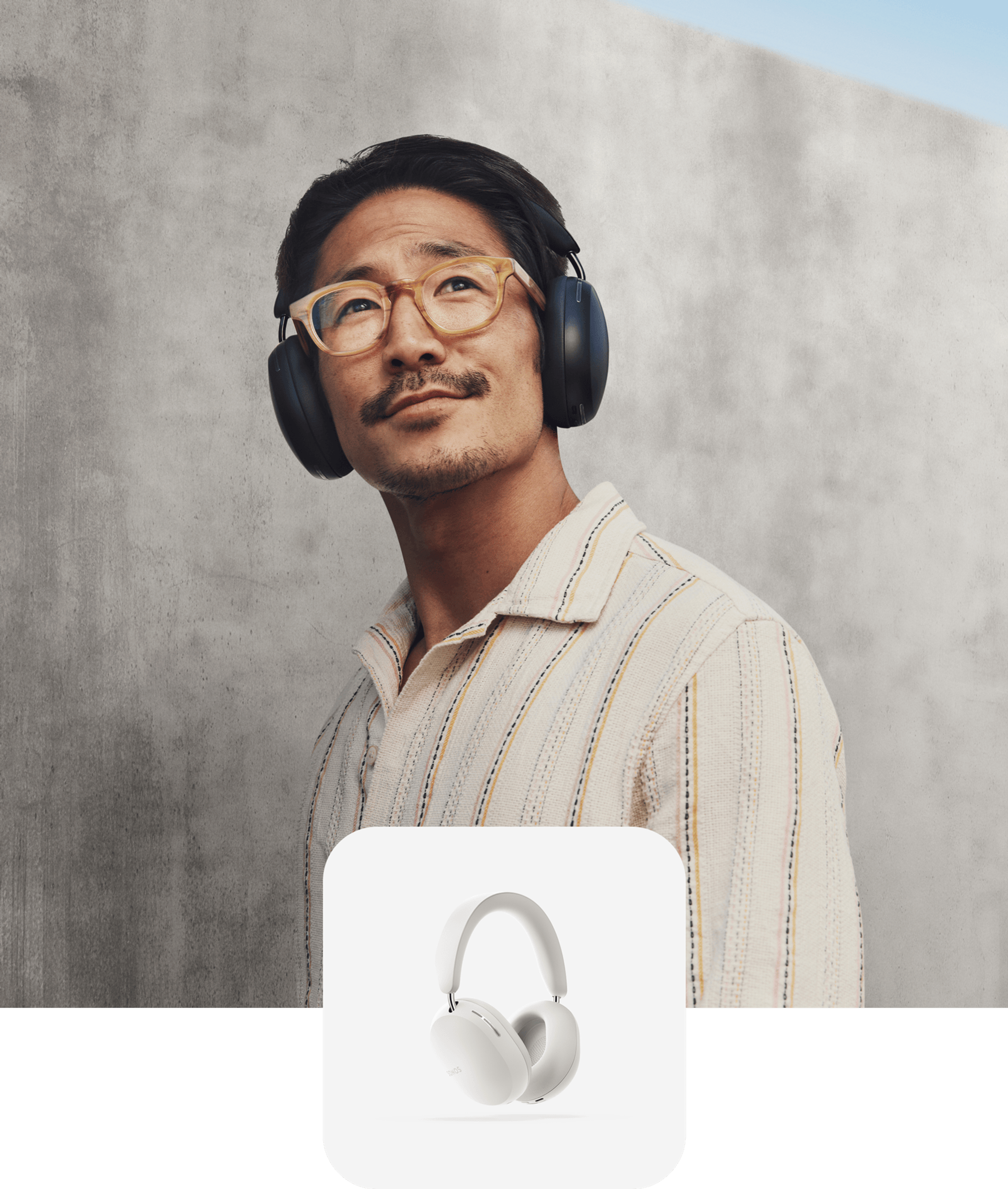 Person smiling listening to music on black Sonos Ace headphones and a white Sonos Ace product tile overlay