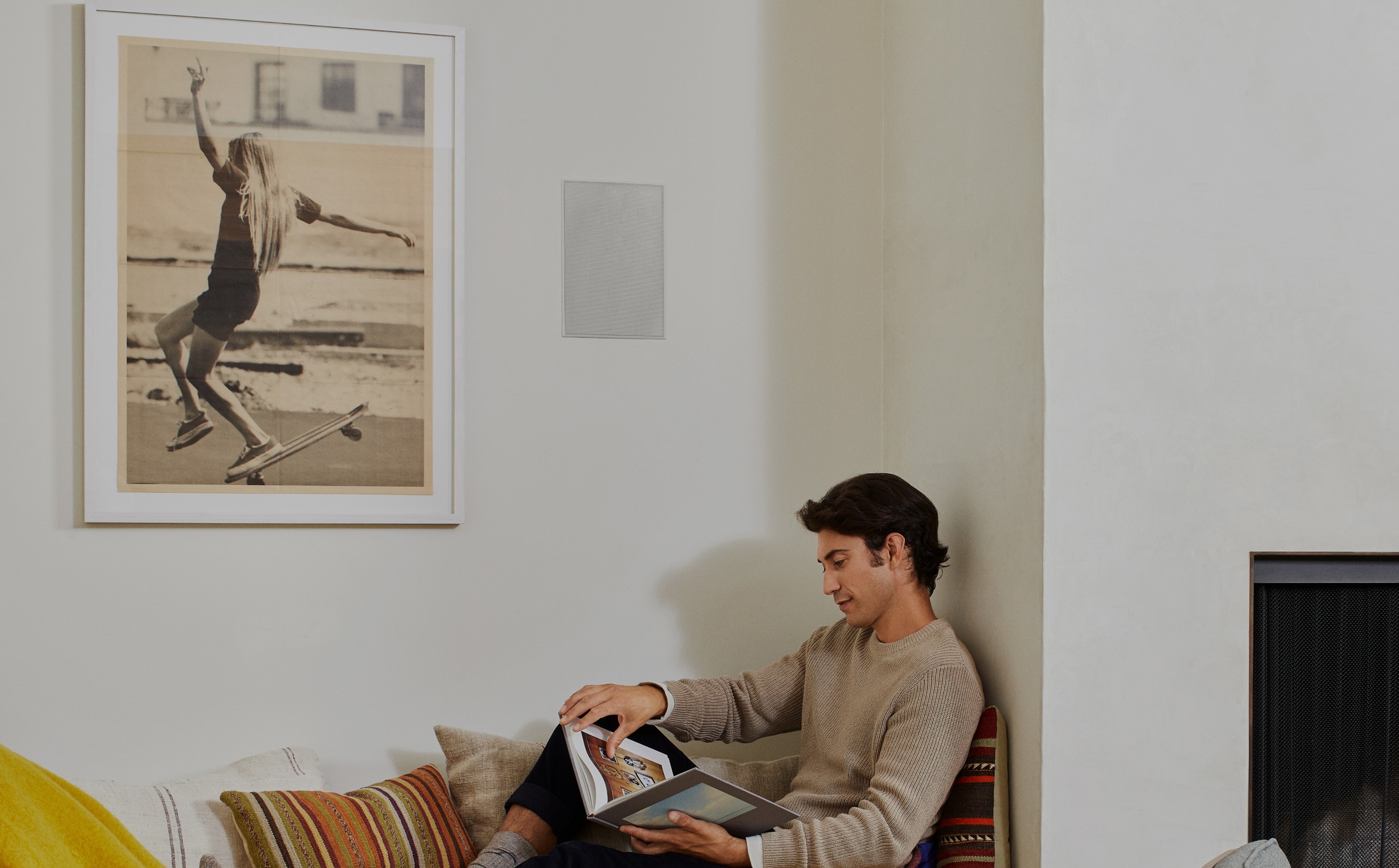 Person reading below their installed Sonos and Sonance In-Wall speakers