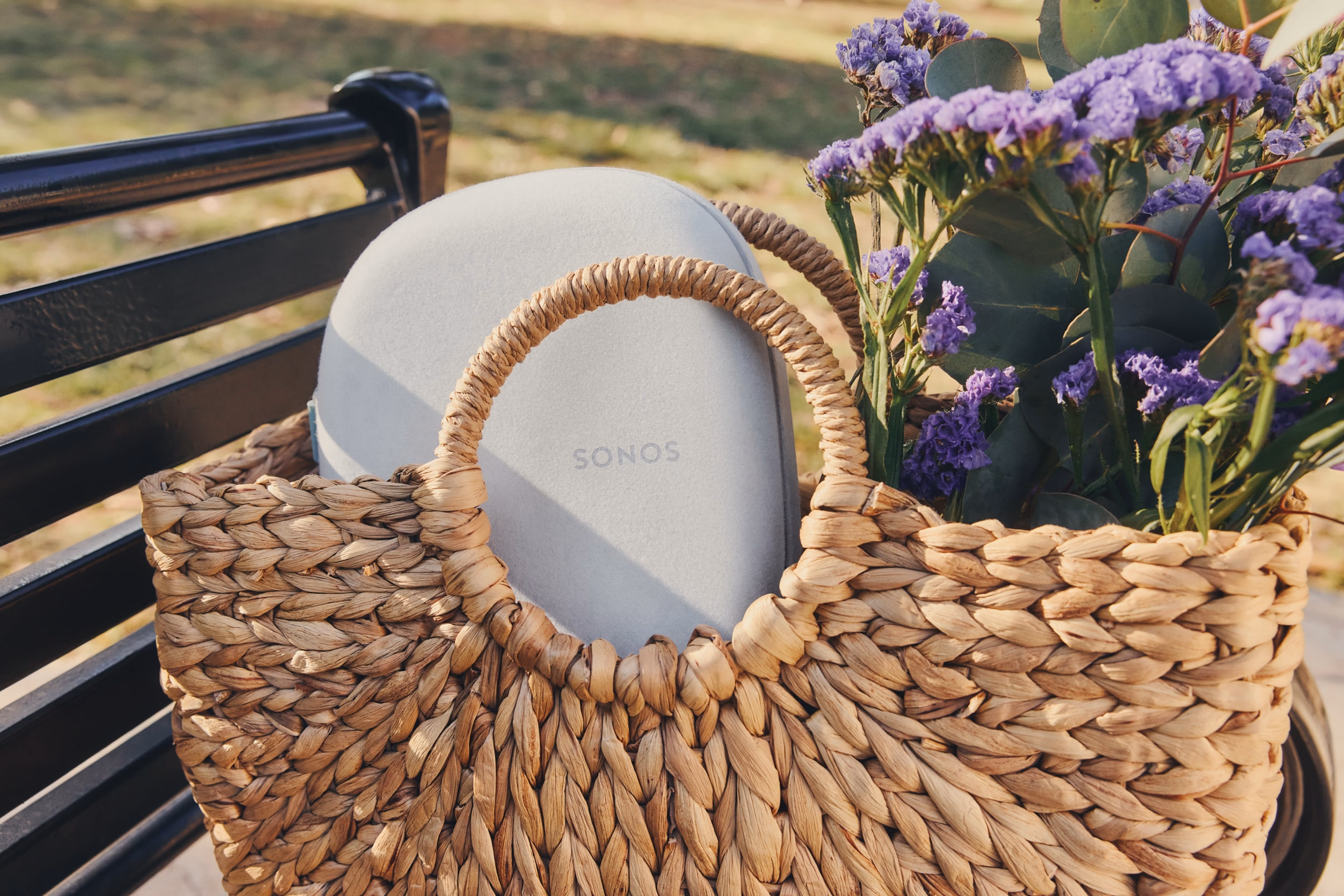 A soft white Sonos Ace case in a woven bag with flowers