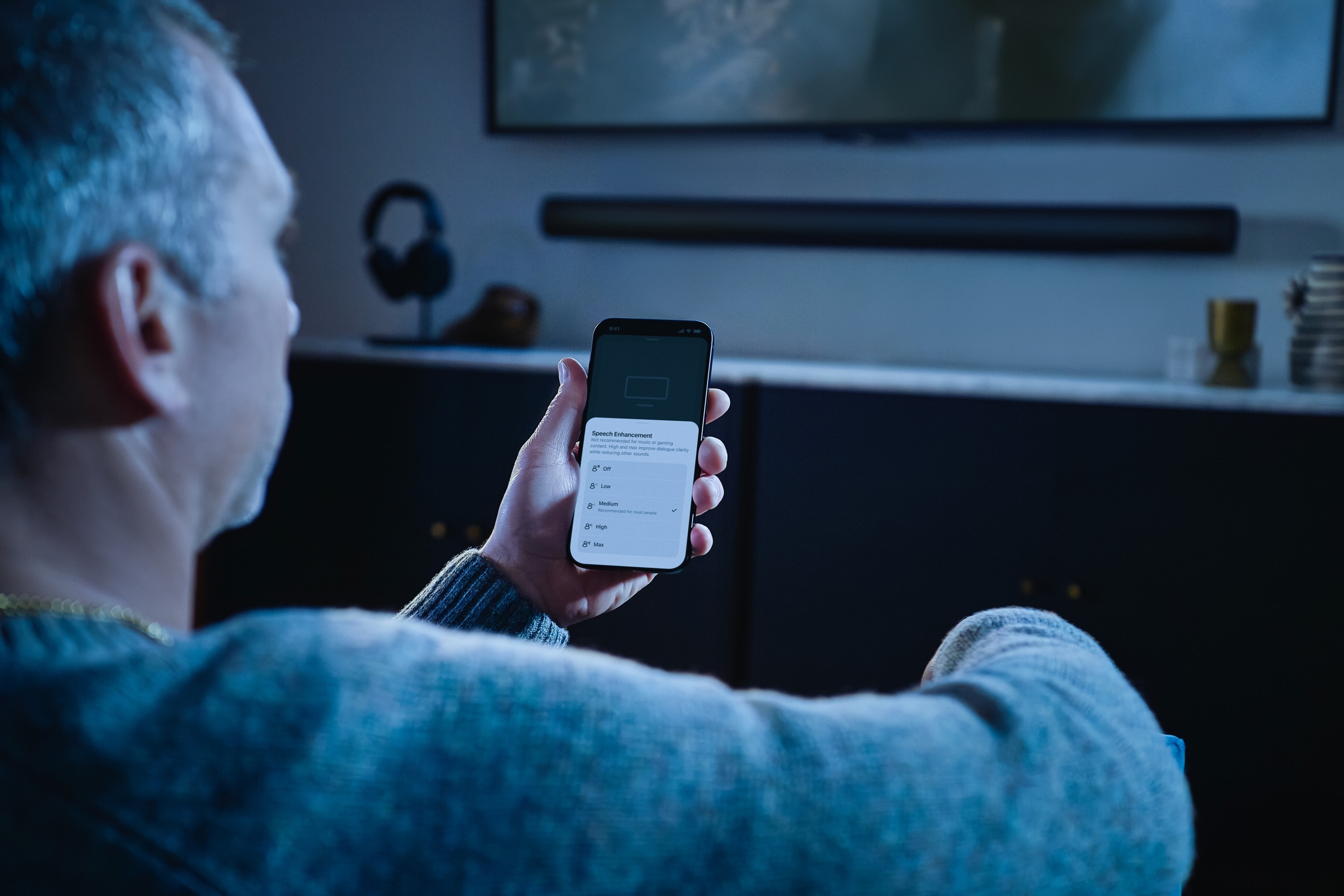 Person looking at the Sonos App on their phone with Arc Ultra in the background