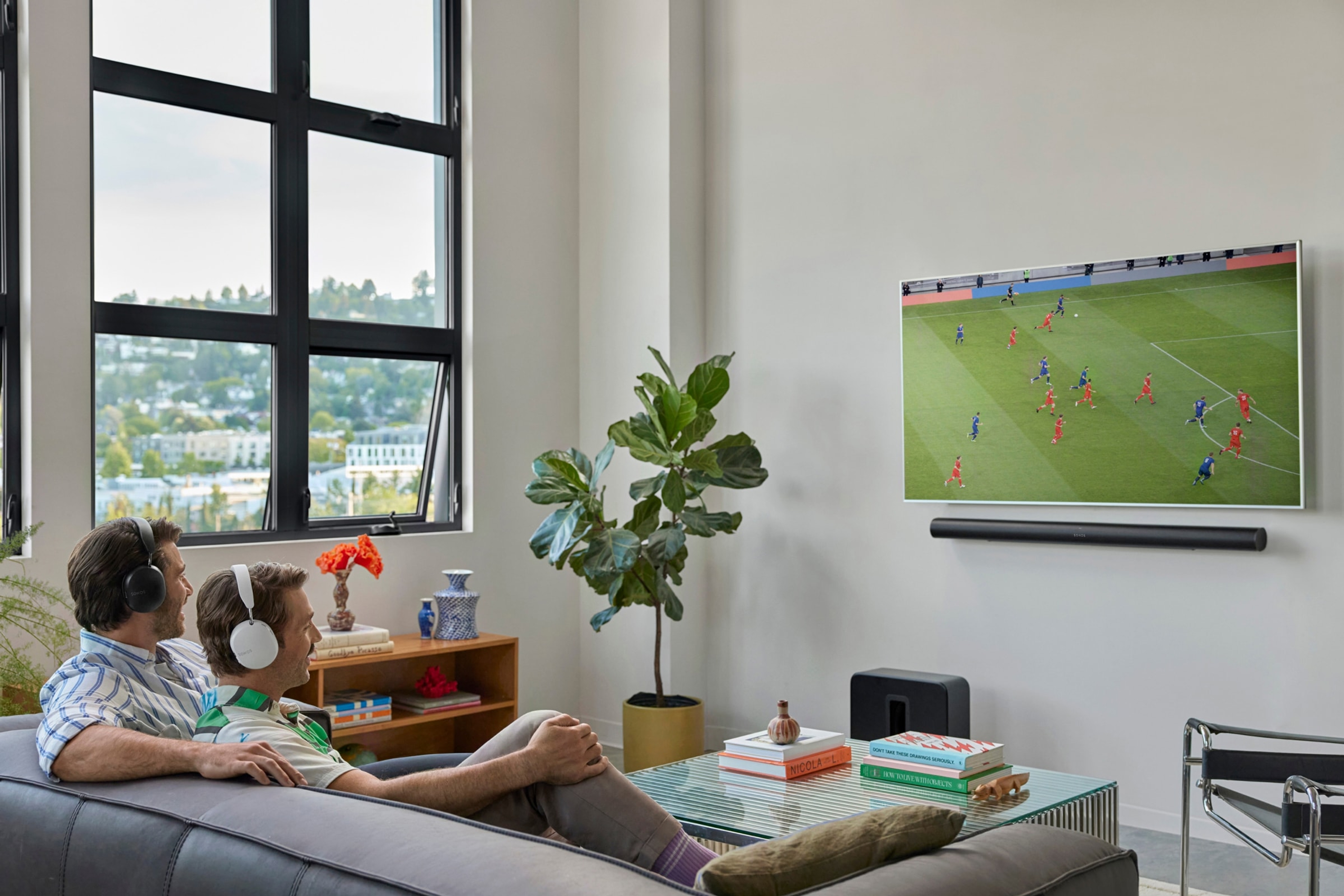 Family seated on a couch watching TV with a black Arc Ultra and a black Sub 4