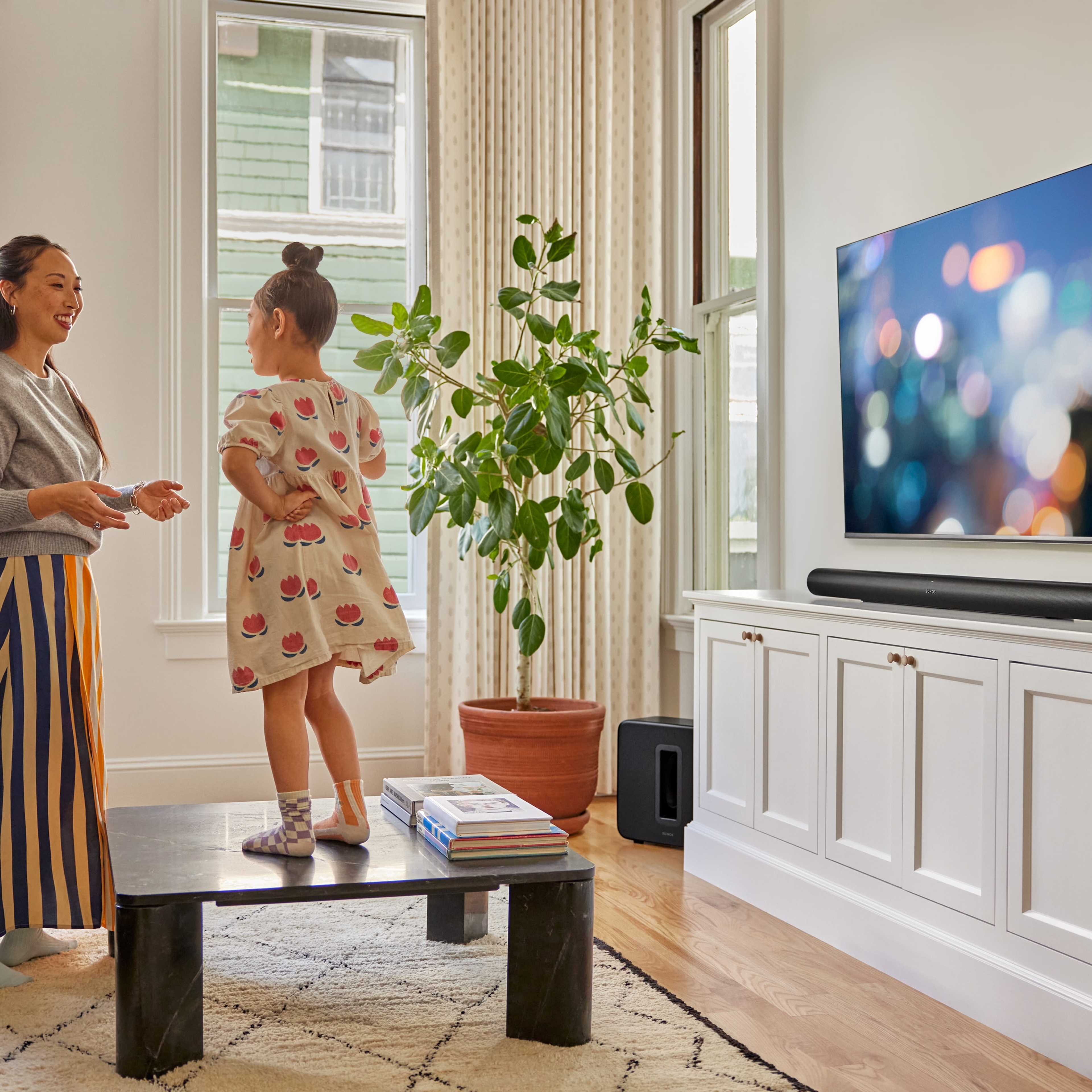 A mother and daughter playing in front of the TV with a black Arc Ultra