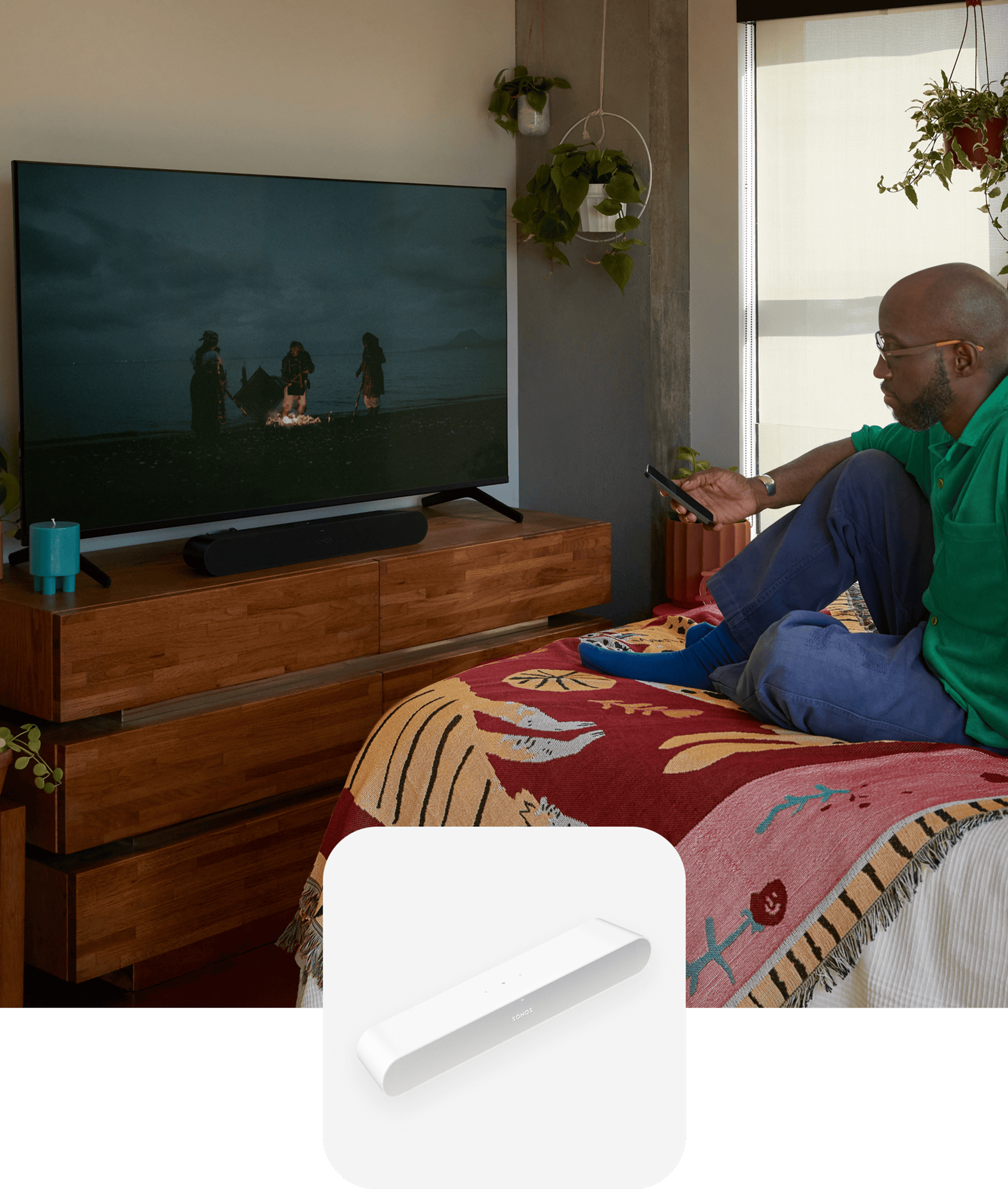 User sitting on their bed watching a film with sound from a black Ray soundbar