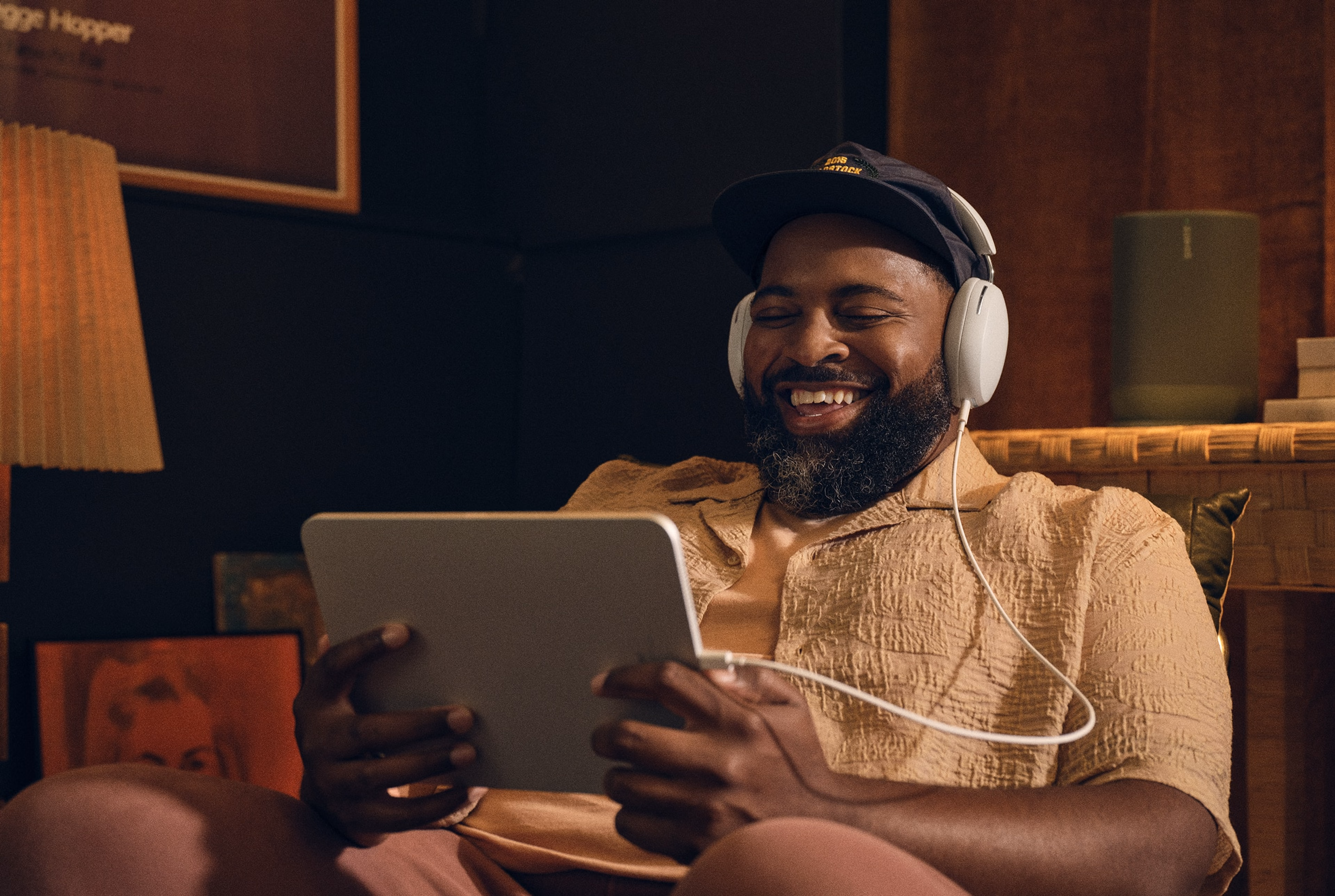 Person sitting in living room listening to white Sonos Ace headphones