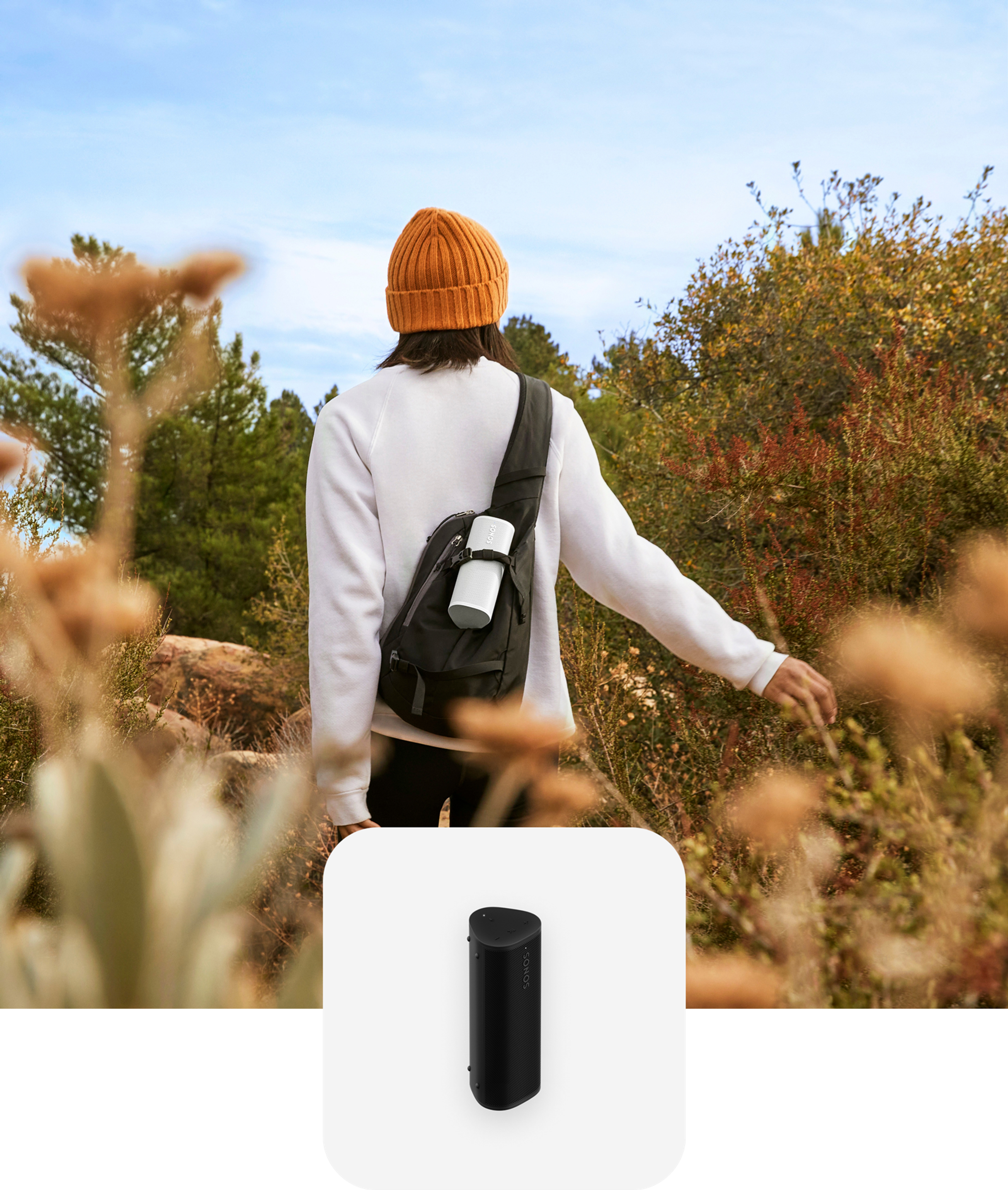 User hiking on a trail listening to a white Roam 2 in their backpack