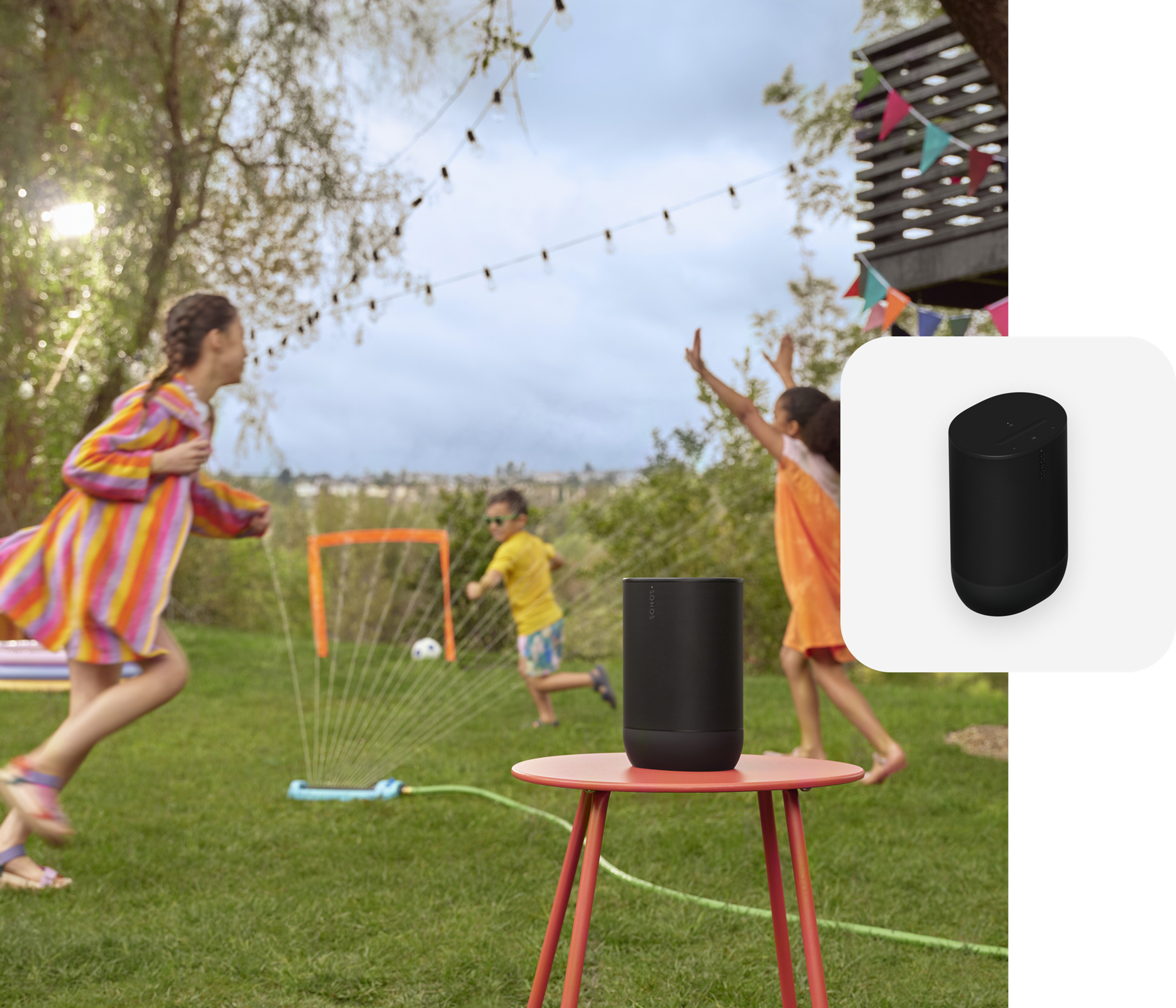 A black Move 2 on a red table while kids play on the lawn in the background