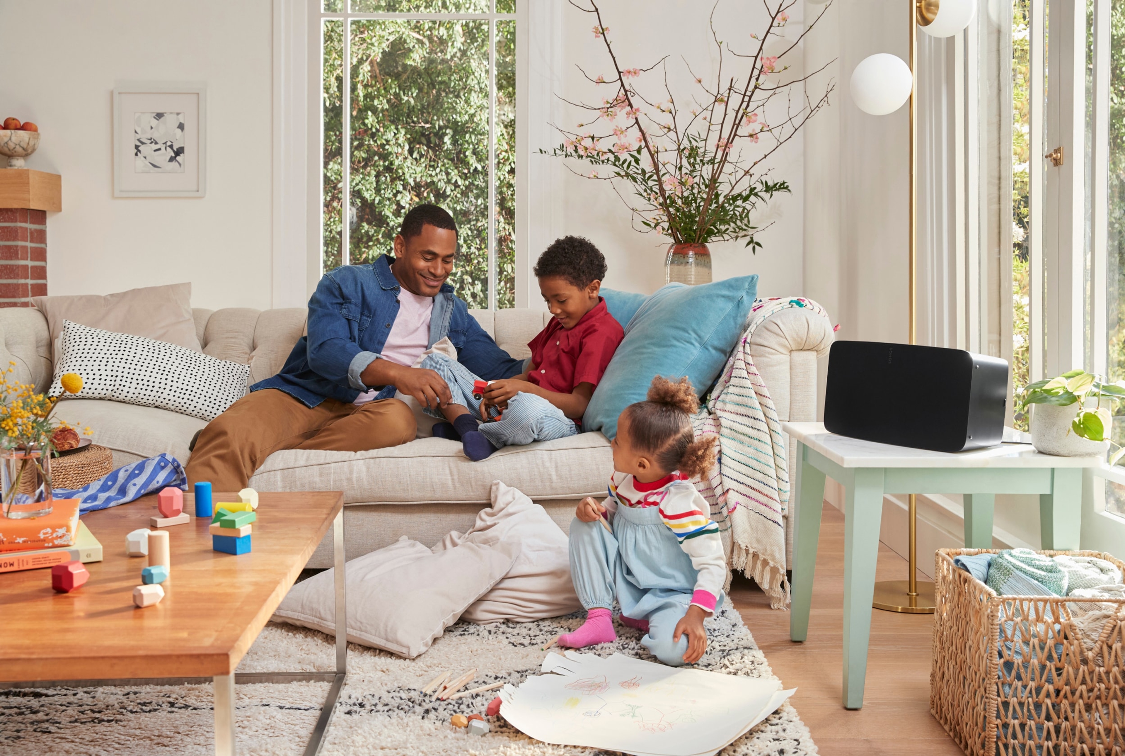 A family on the couch in their living room listening to a Black Sonos Five