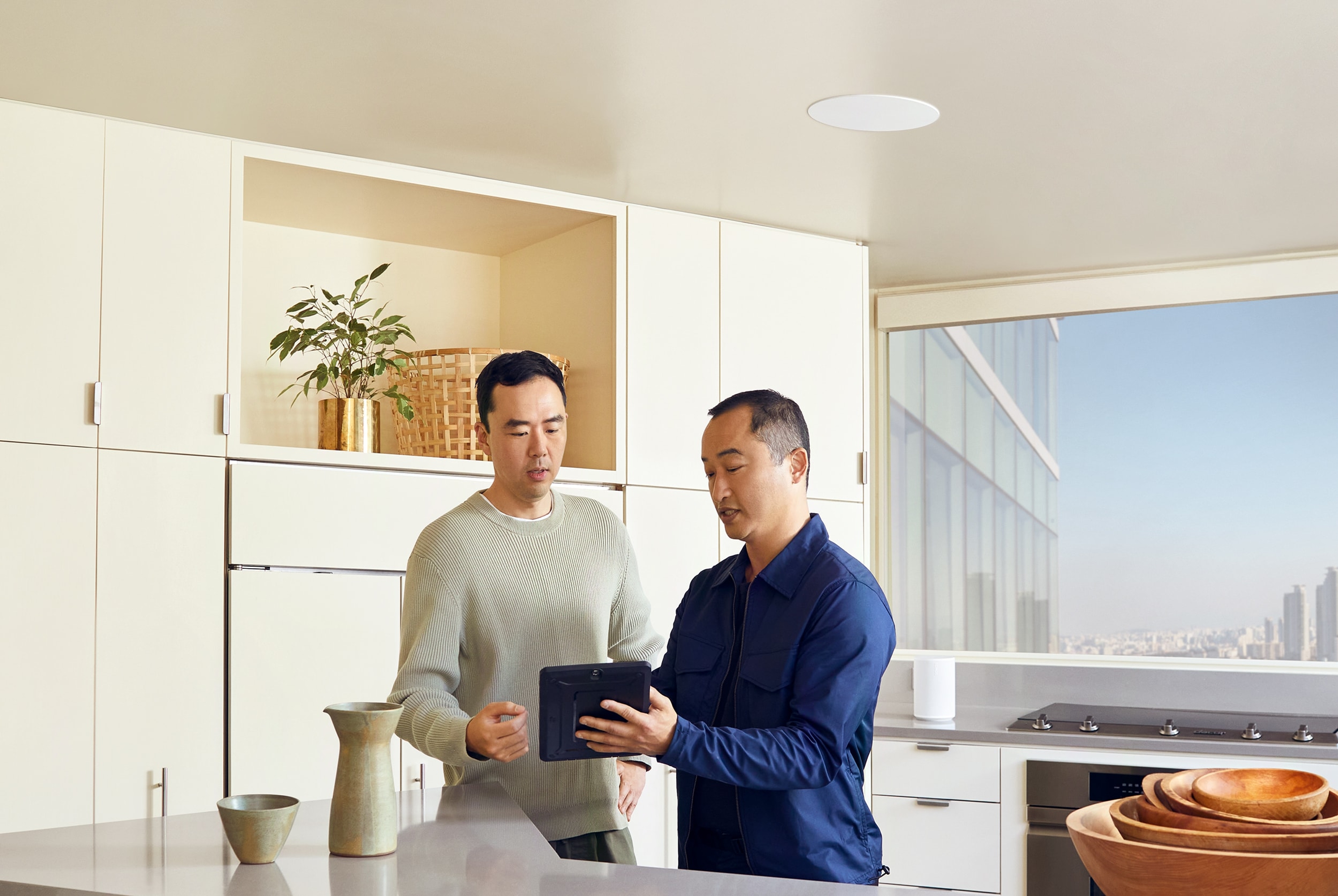 Two men chatting in the kitchen with Sonance in-ceiling speakers installed above a kitchen island