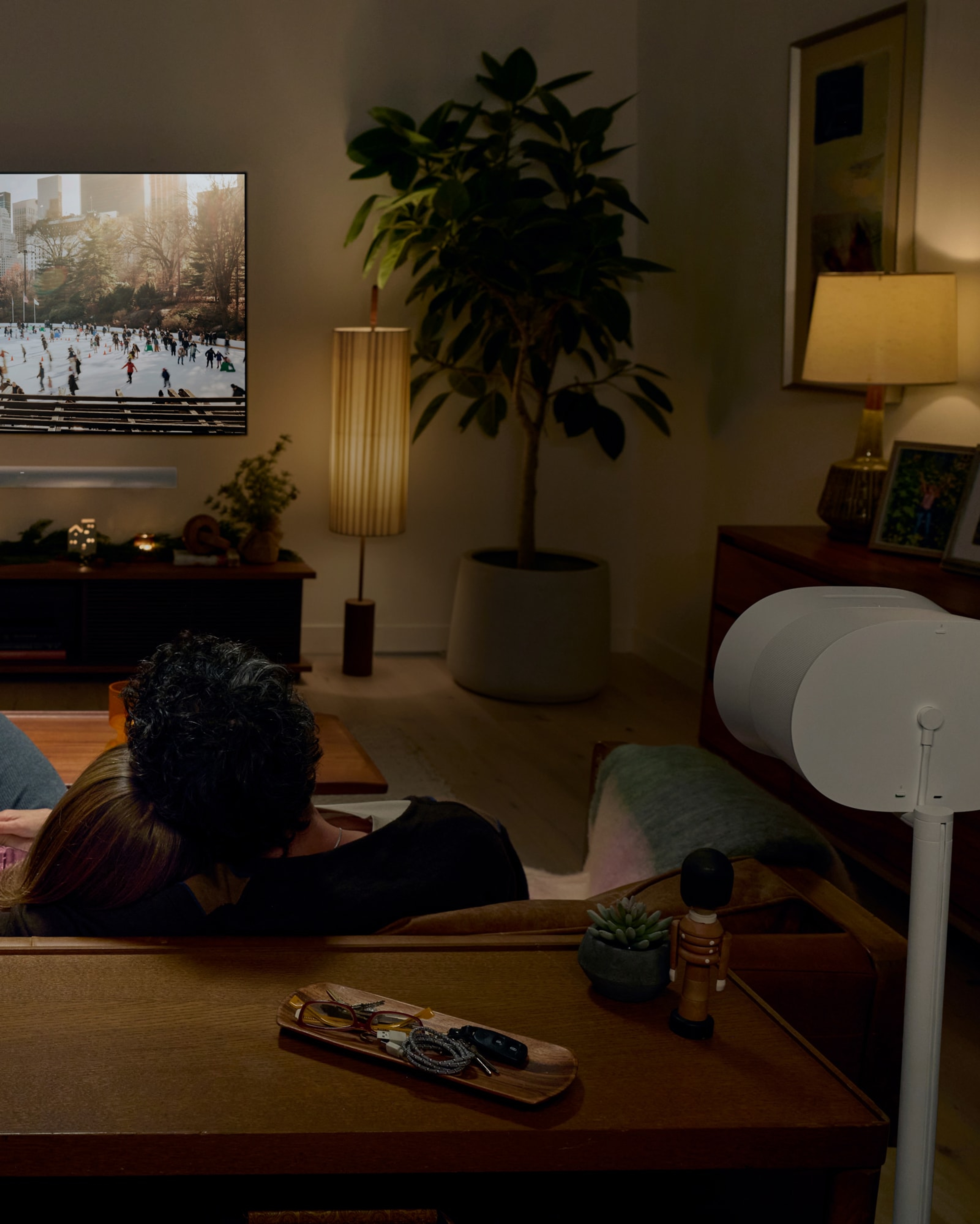 A couple on the couch watching a holiday film with a Sonos Arc Ultra and Era 300 surround sound set
