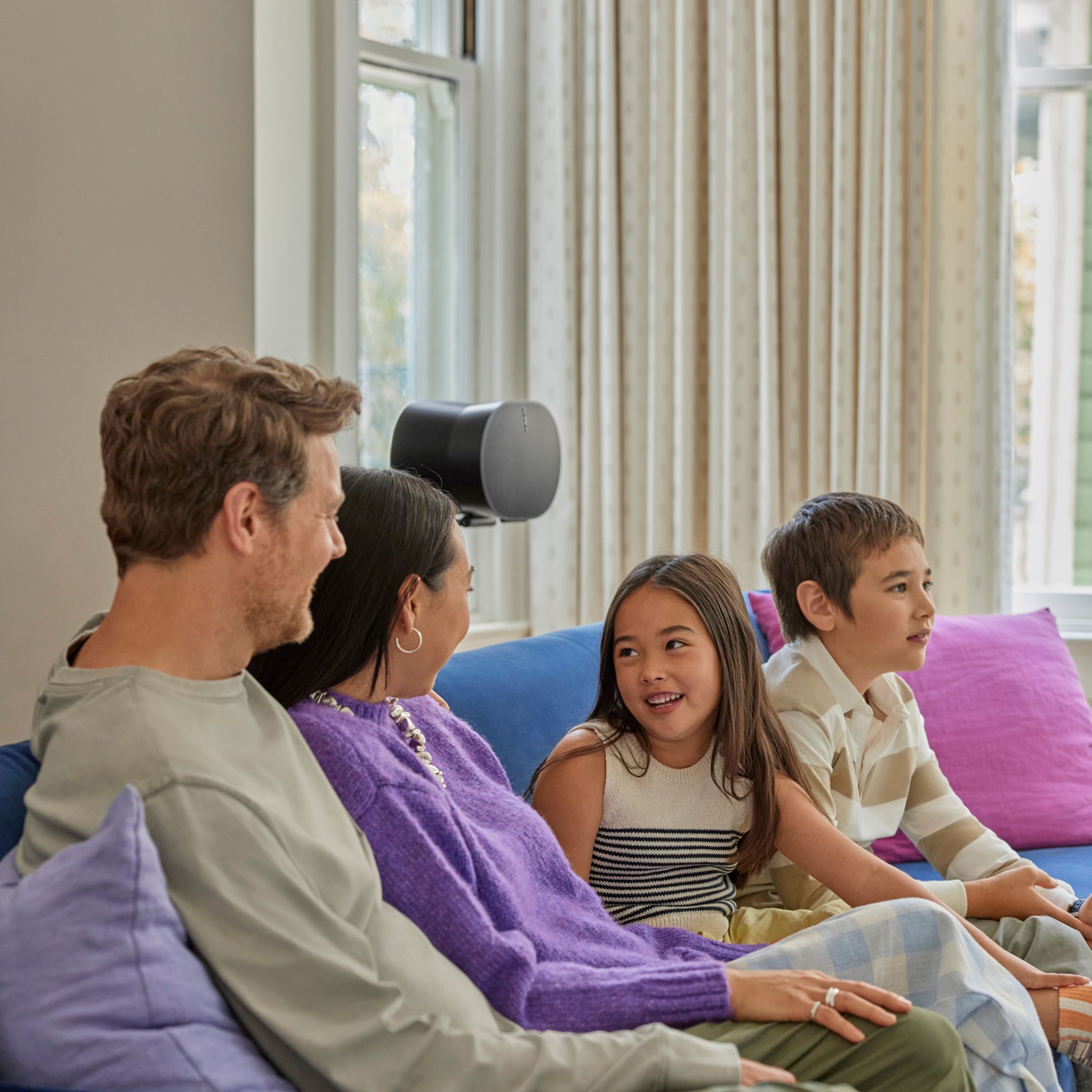 Family conversing on a couch in front of a black Era 300 on a stand
