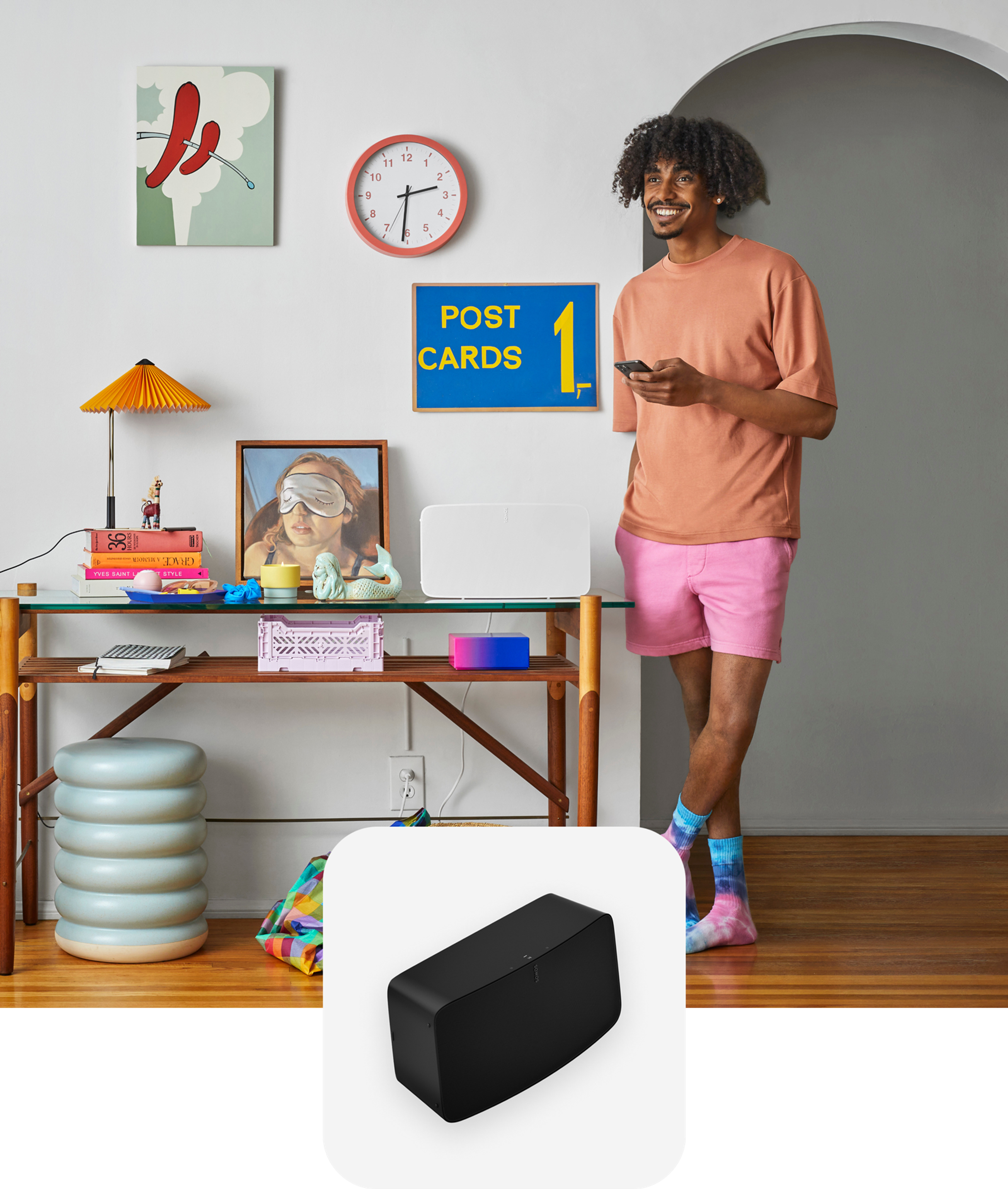 User standing next to his white Sonos Five speaker controlling it with the Sonos app