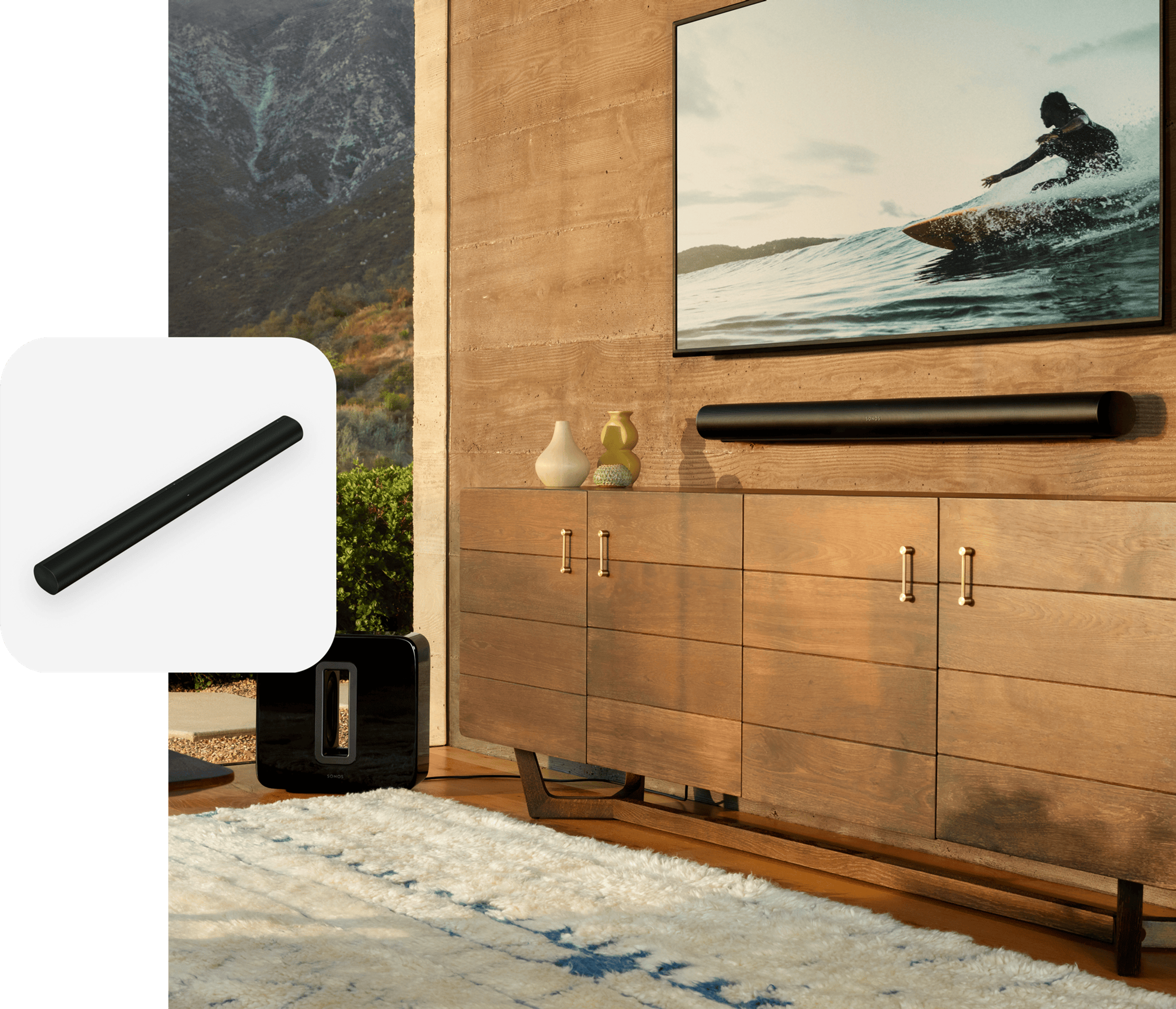 A wall-mounted Sonos Arc below a TV in a living room with a black Sonos Sub