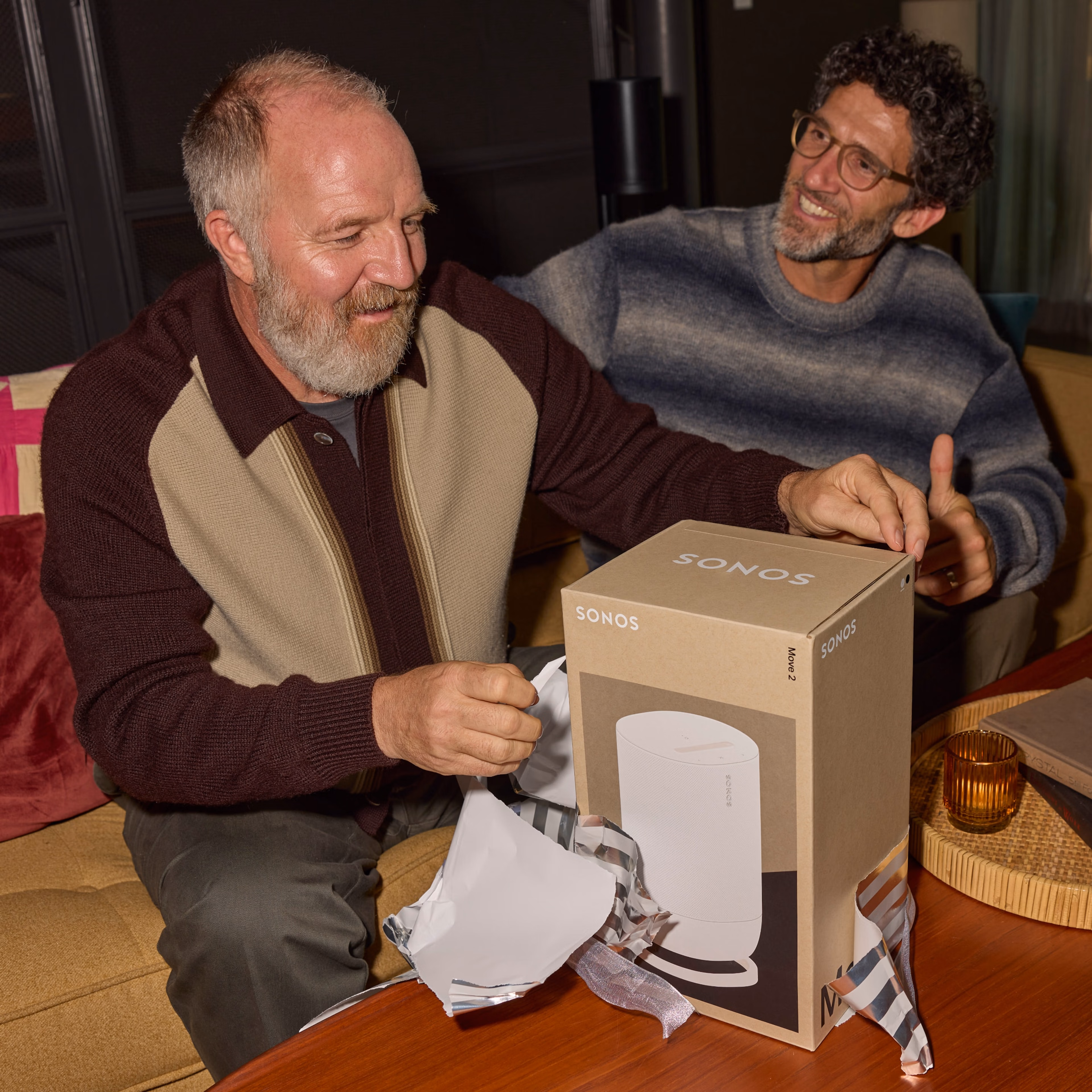 Two people smiling and opening a gift-wrapped Sonos Move 2