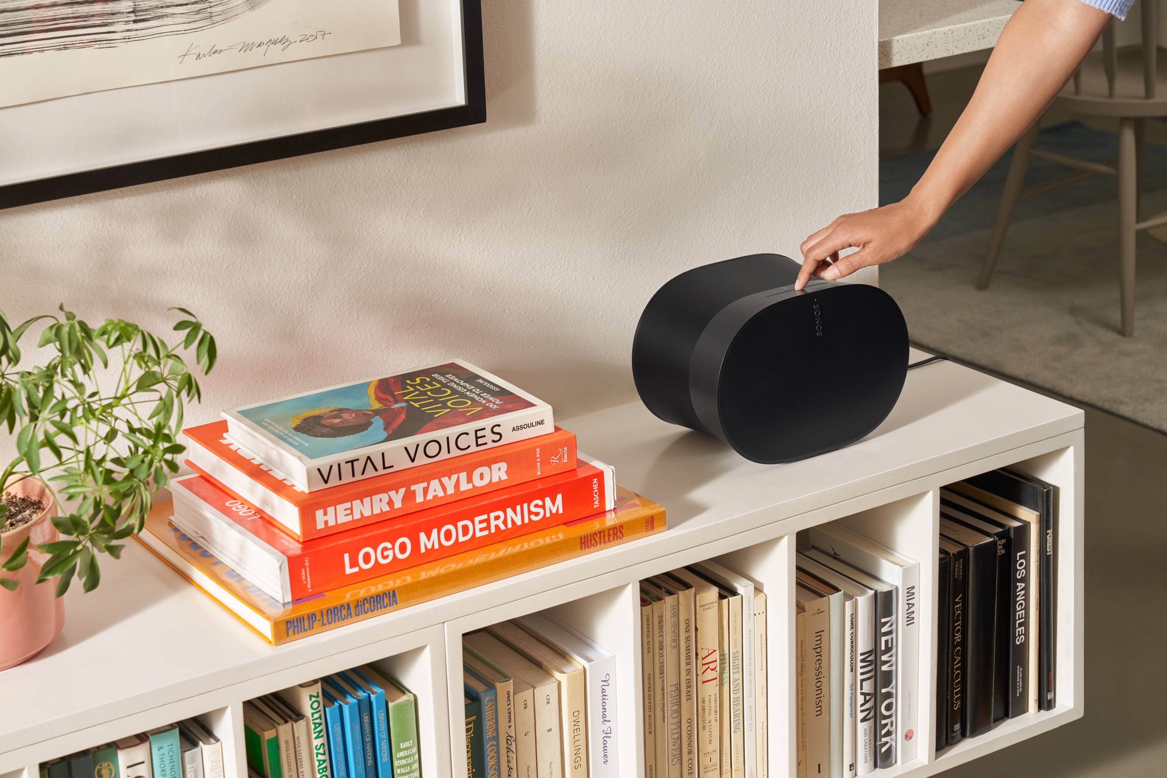 Woman using the touch controls of a black Era 300 on a bookshelf