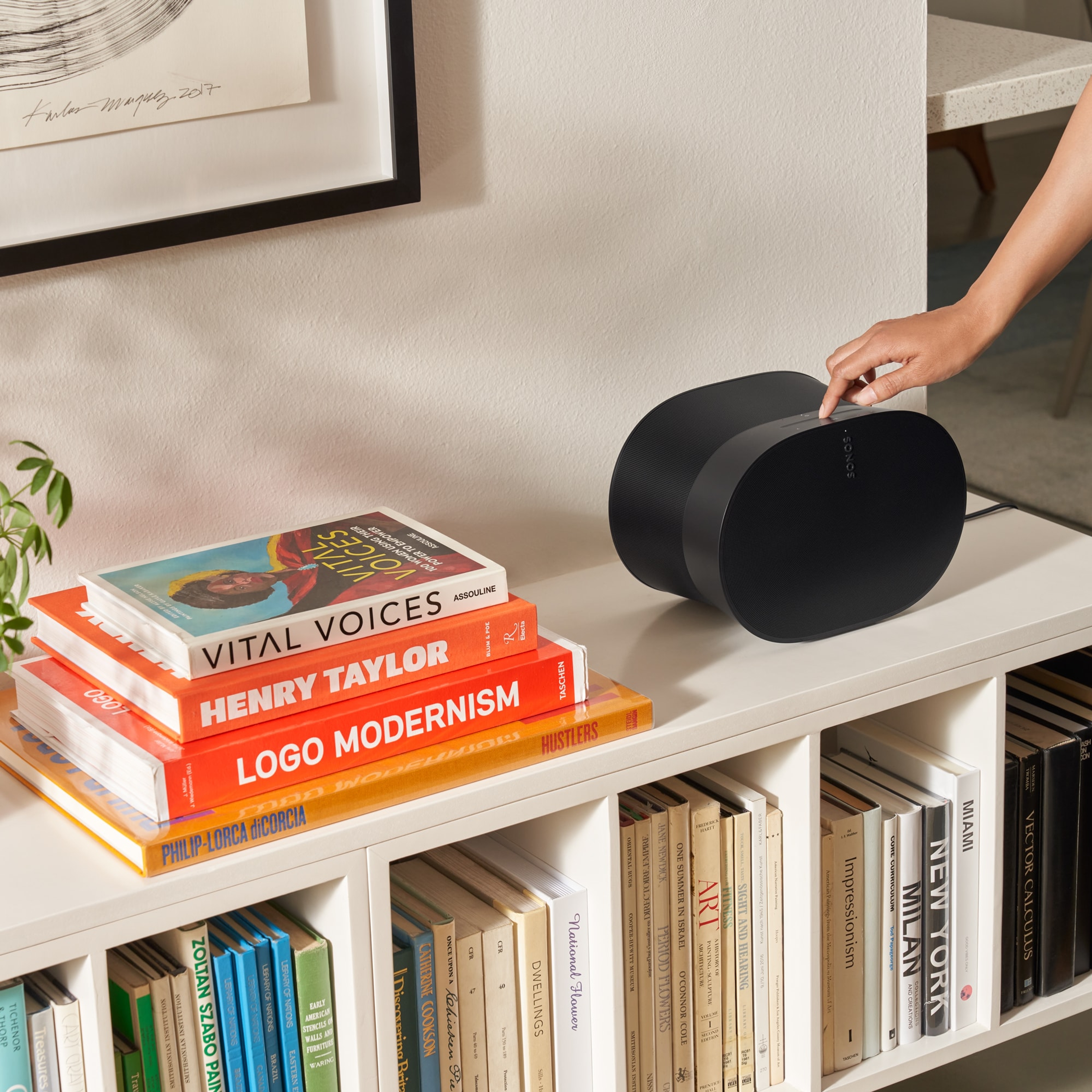 Woman using the touch controls of a black Era 300 on a bookshelf