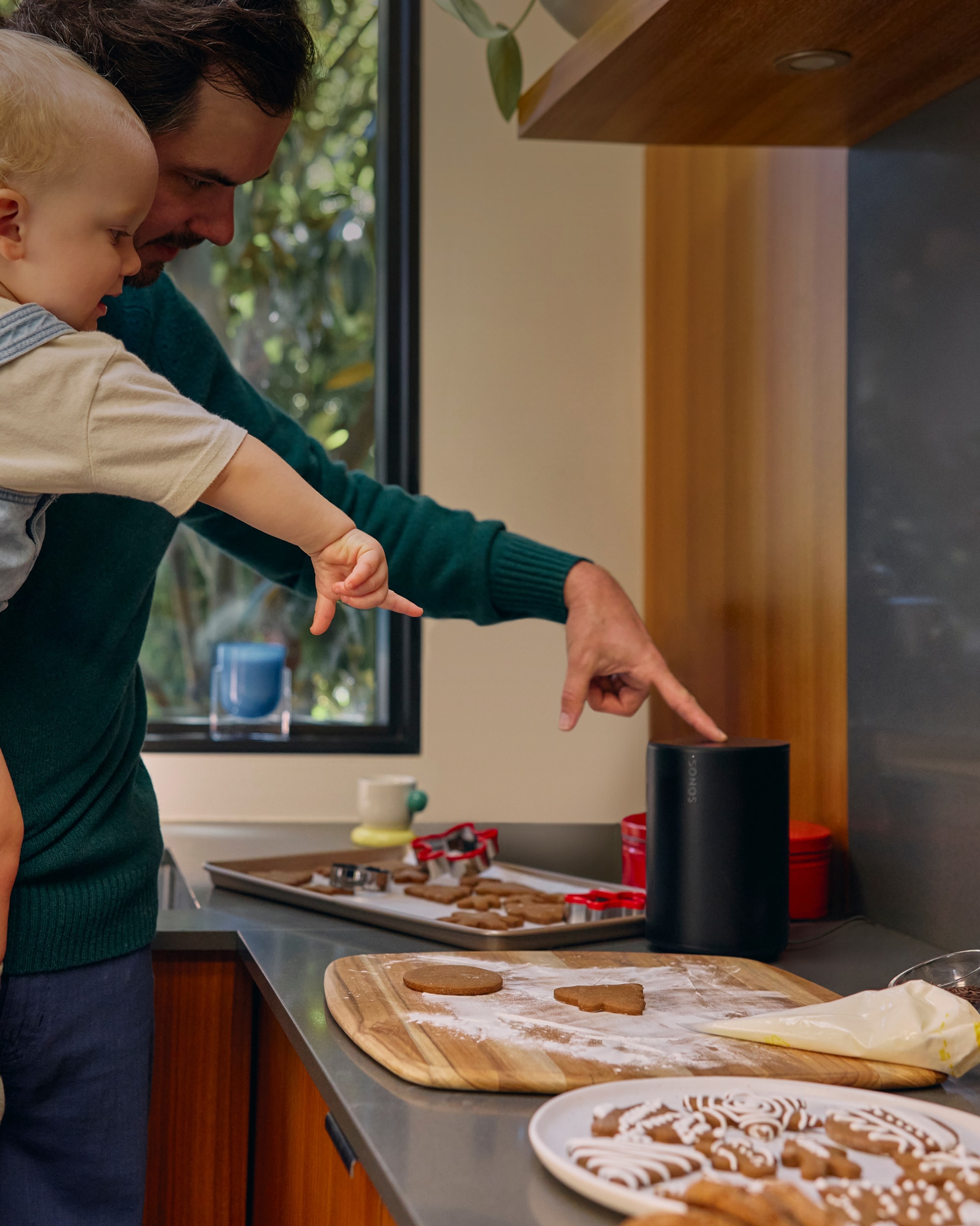 Father and child's hands touching Era 100 next to holiday cookies