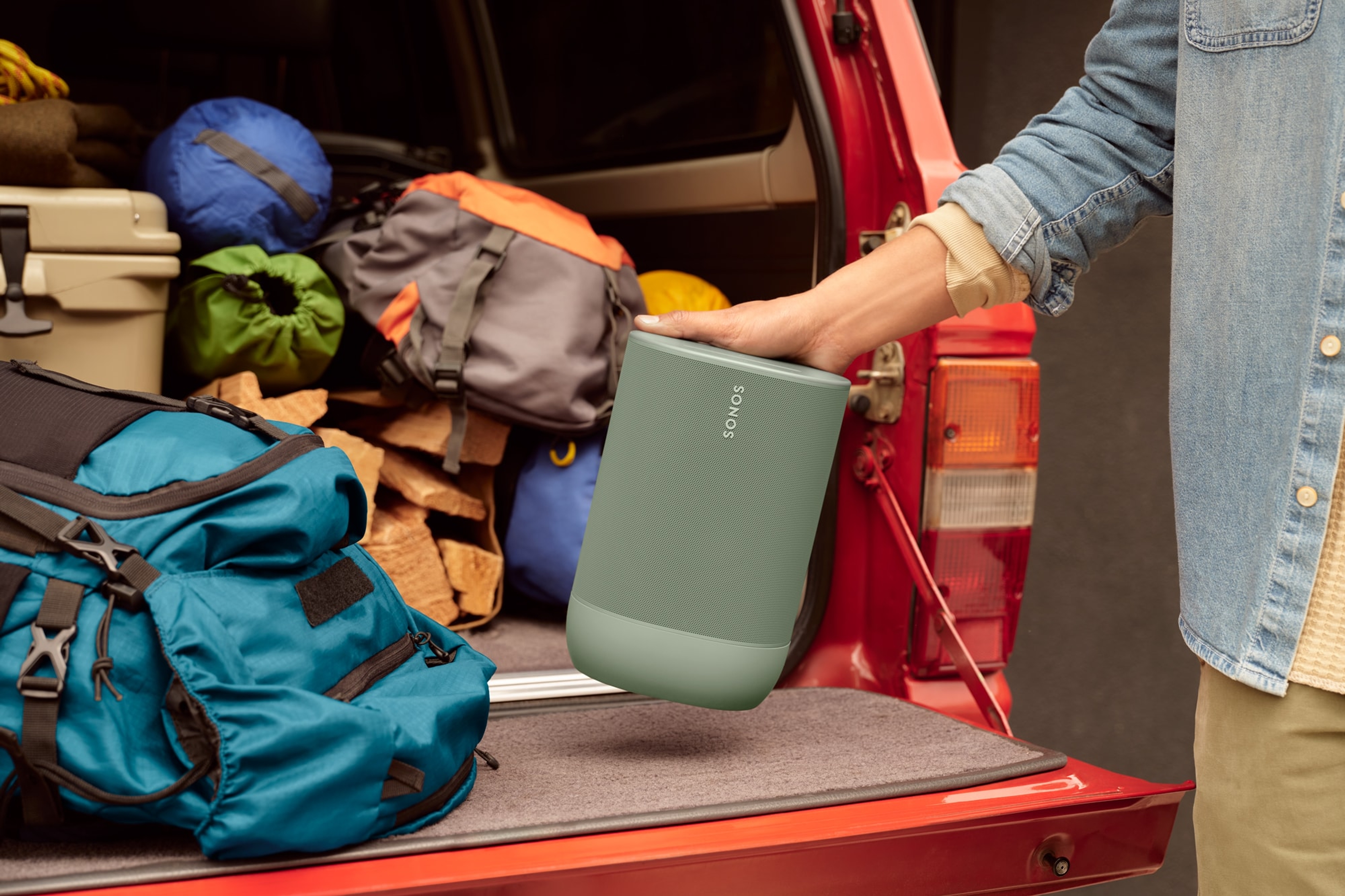 Image of a man packing up his truck for a camping trip carrying a Sonos Move 2 in Olive