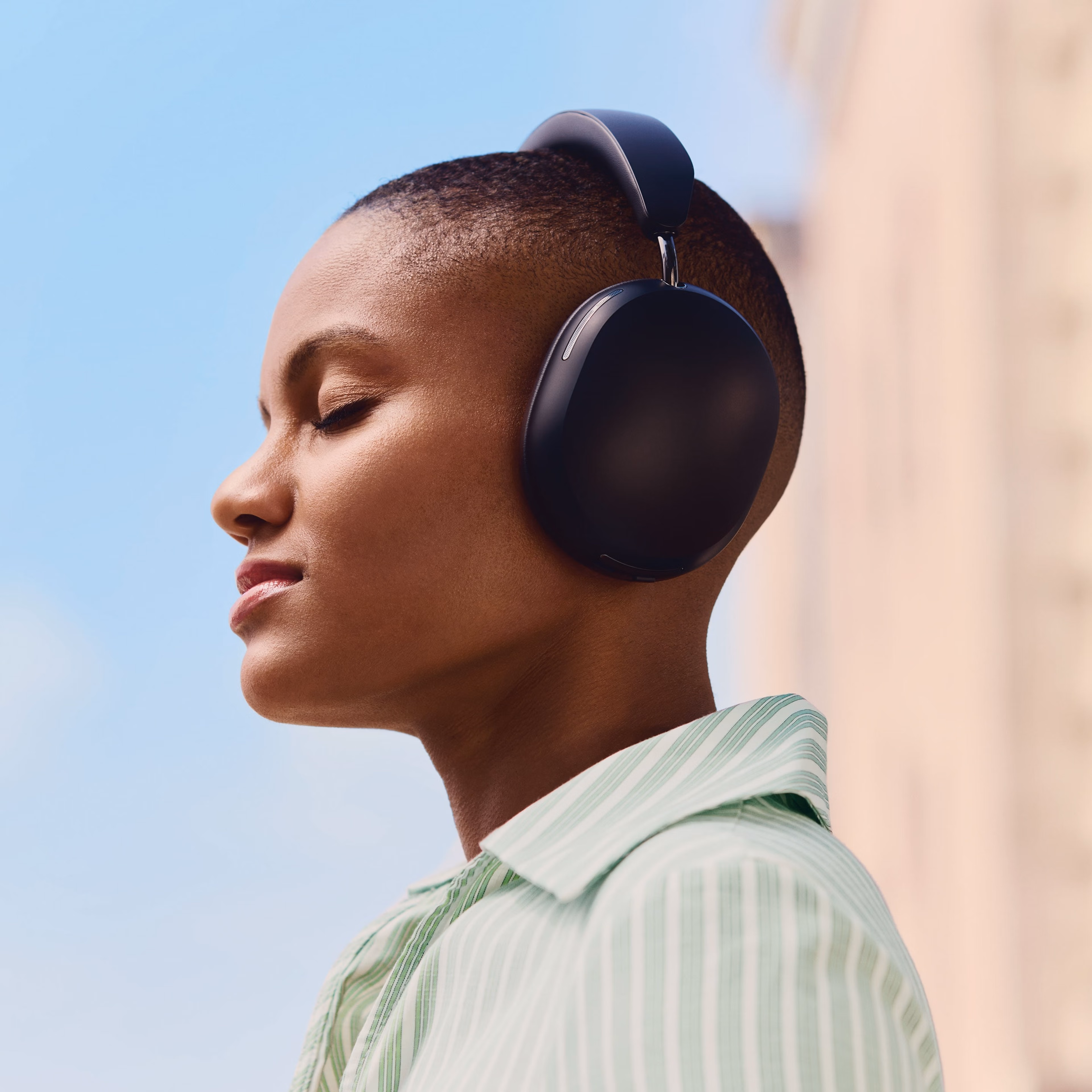 Male user wearing a pair of black Sonos Ace headphones while seated in a chair