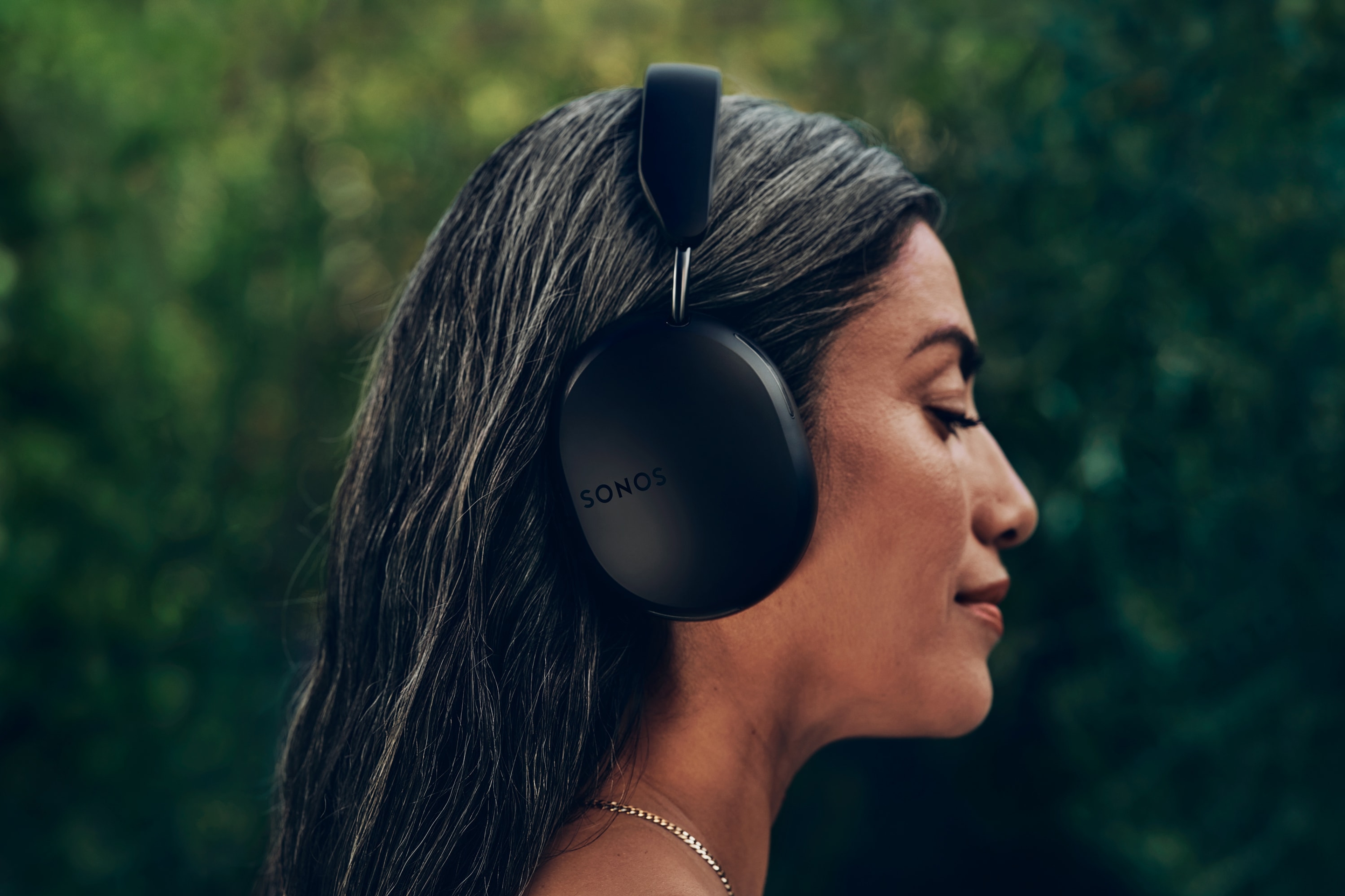 Una mujer de perfil lleva puesto un par de audífonos Sonos Ace en negro