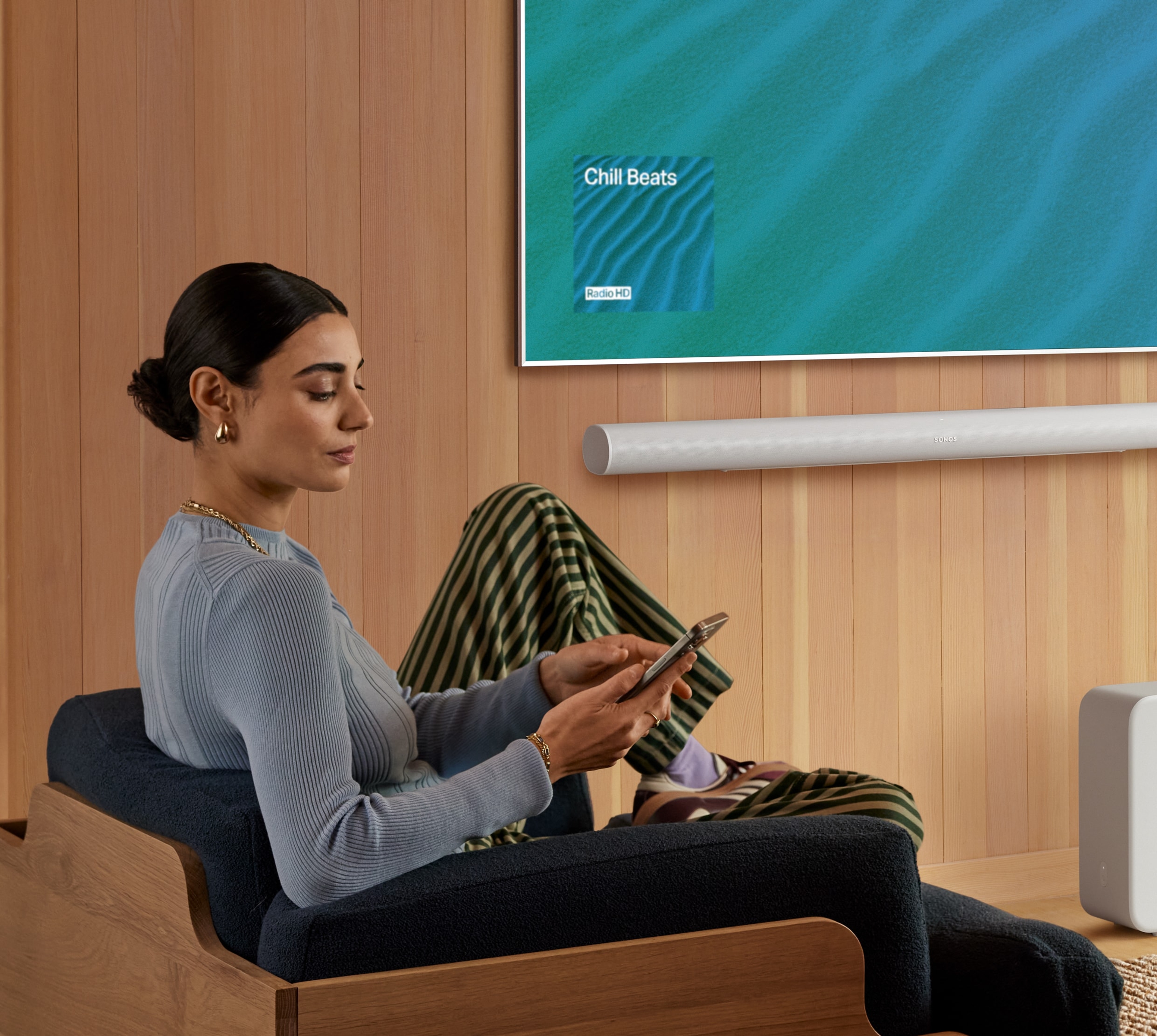 Person using a phone with Sonos Arc Ultra and TV in the background