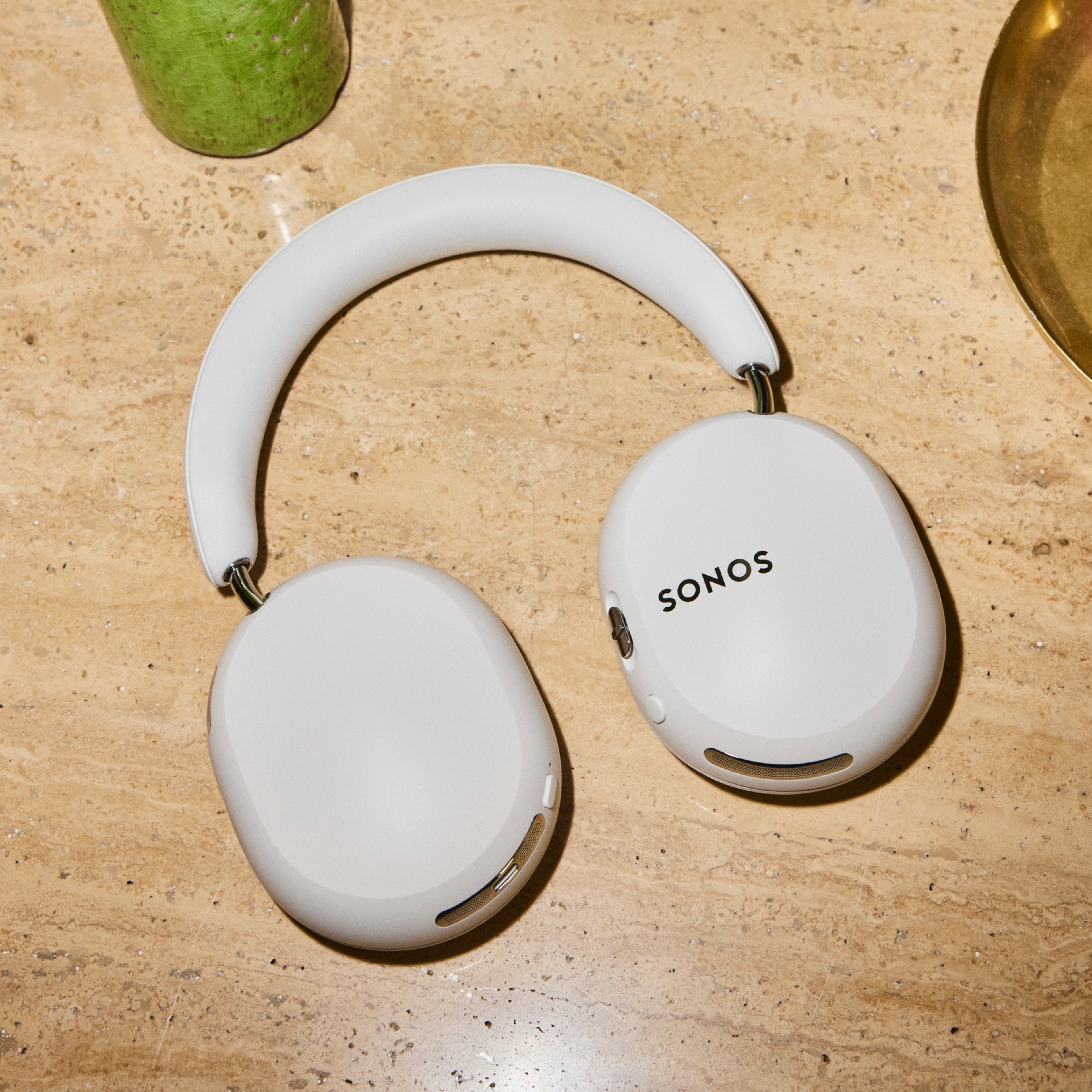 White Sonos Ace Ultra headphones laying flat on a wooden tabletop
