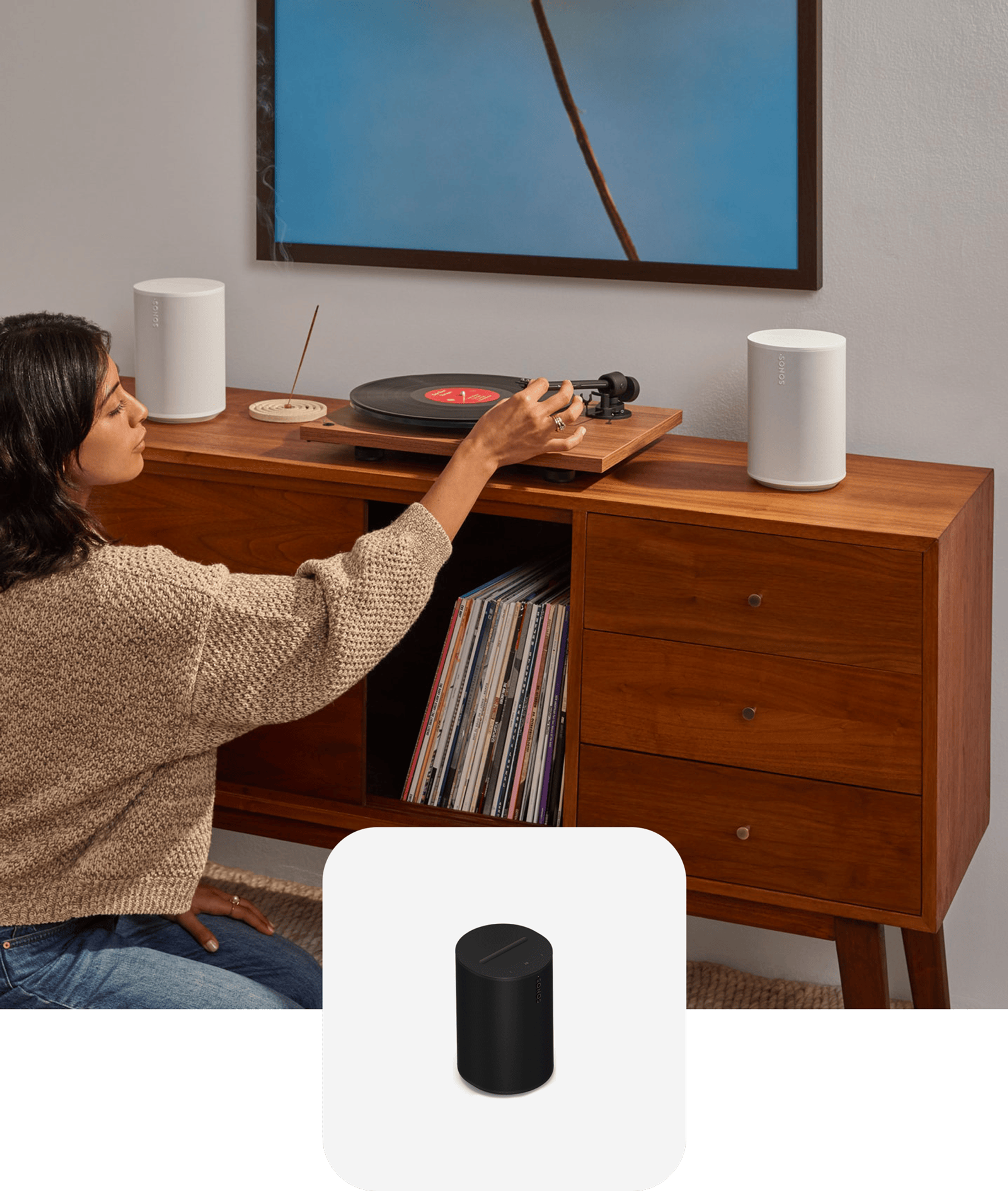 A pair of white Sonos Era 100 SL speakers connected to a turntable while someone drops the needle on a vinyl record