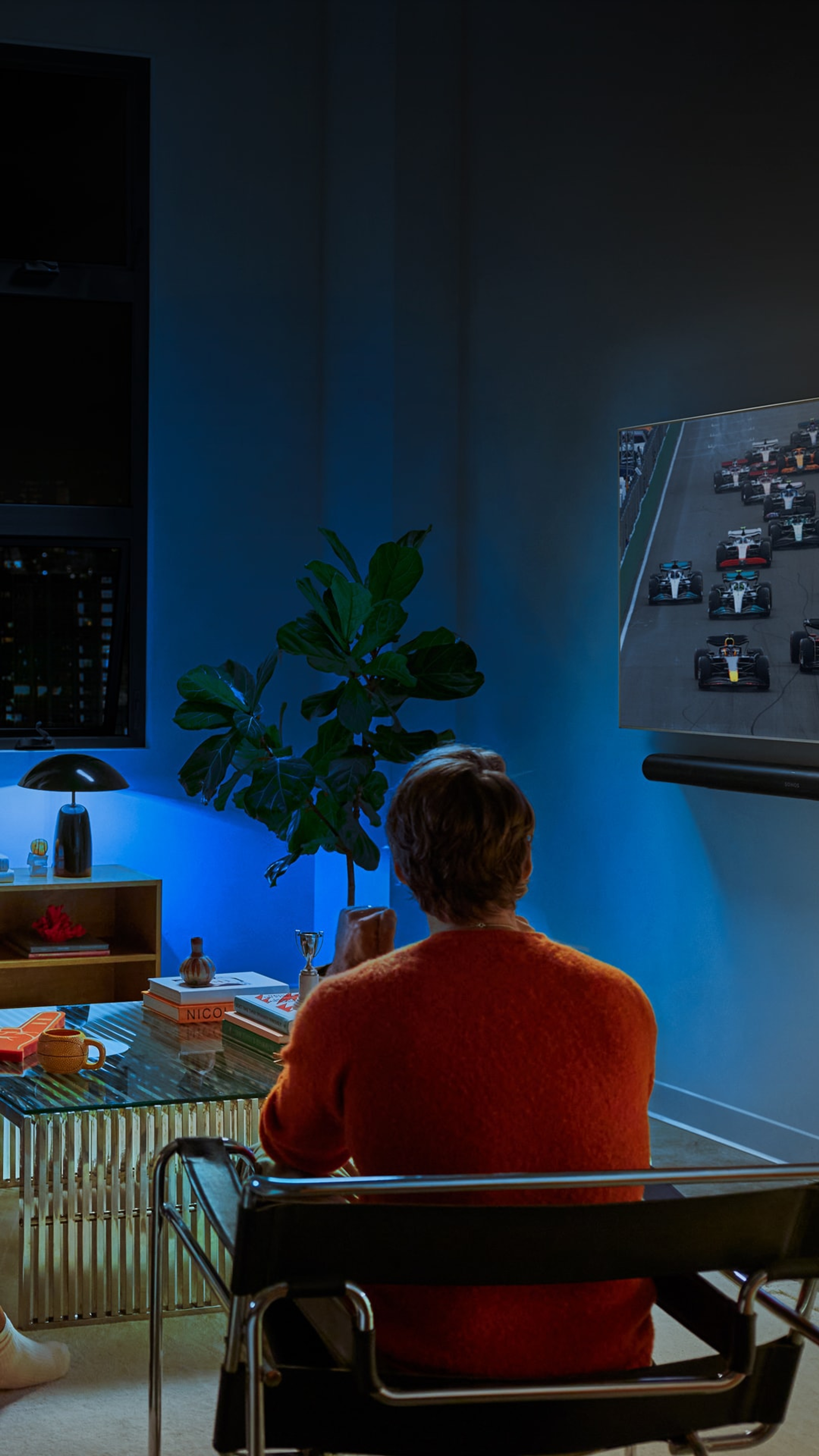 Un groupe d'amis en train de regarder la F1 avec un système home cinéma Sonos et un éclairage Philips Hue bleu