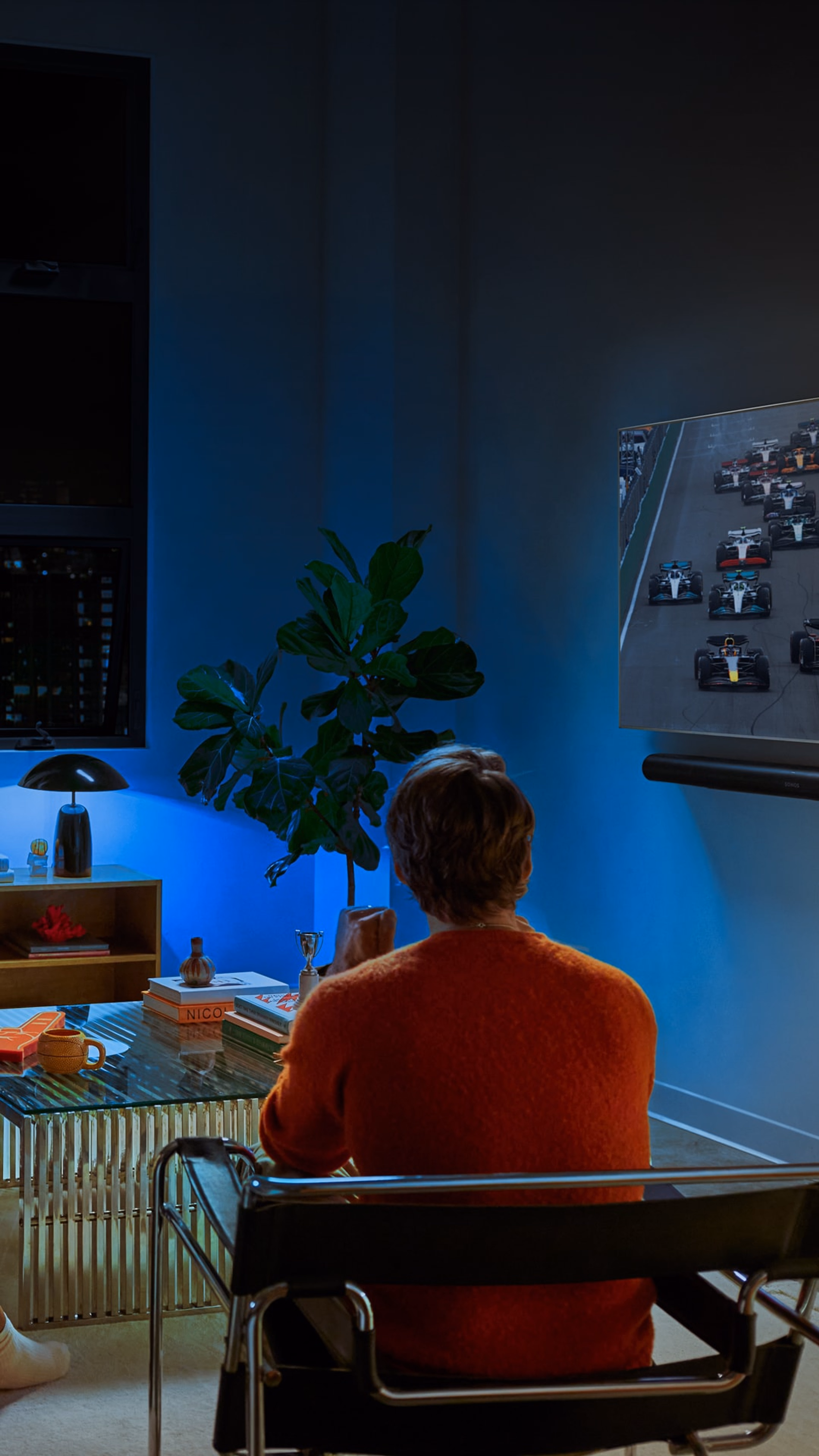Un groupe d'amis en train de regarder la F1 avec un système home cinéma Sonos et un éclairage Philips Hue bleu