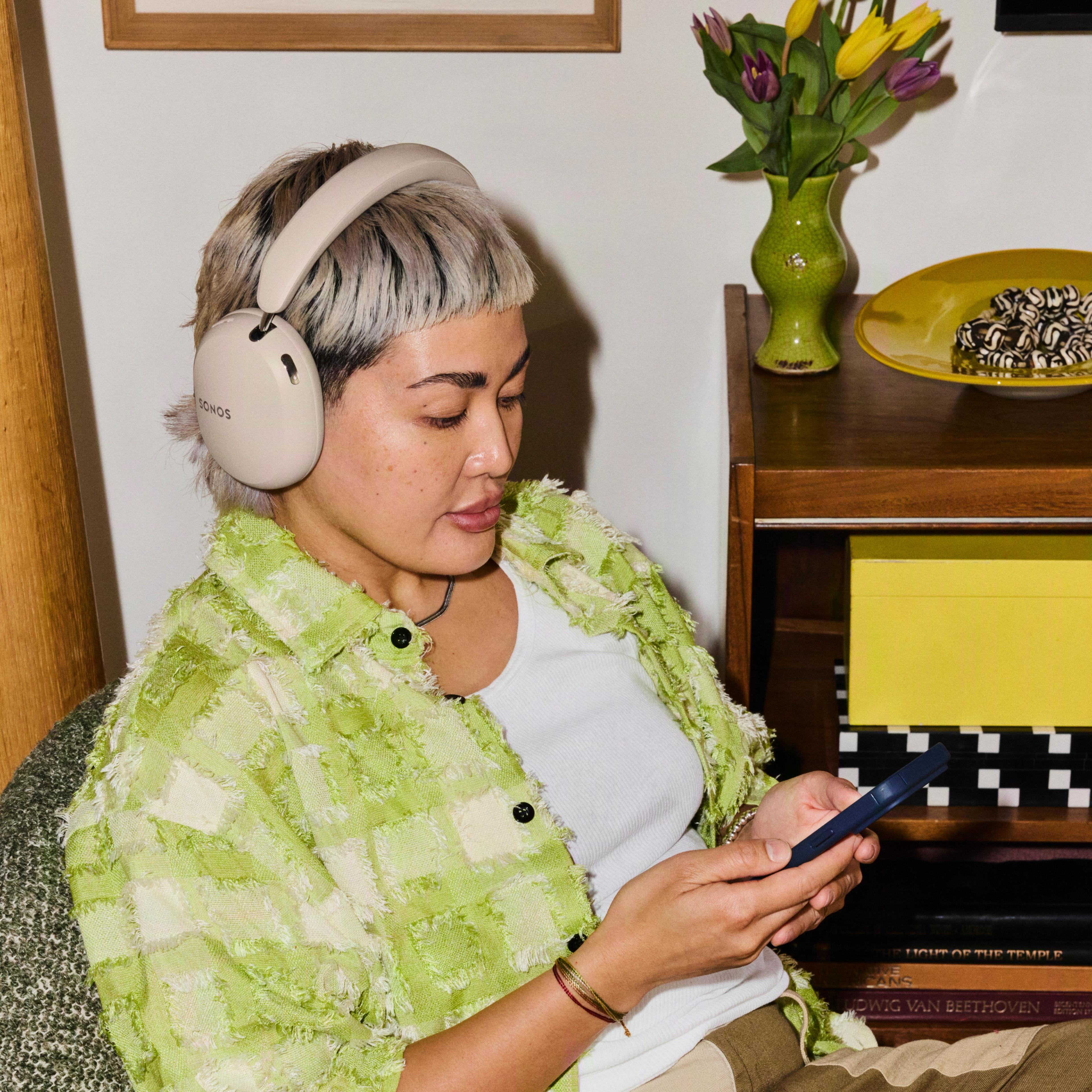 Sonos Ace Ultra headphones on woman holding a cell phone