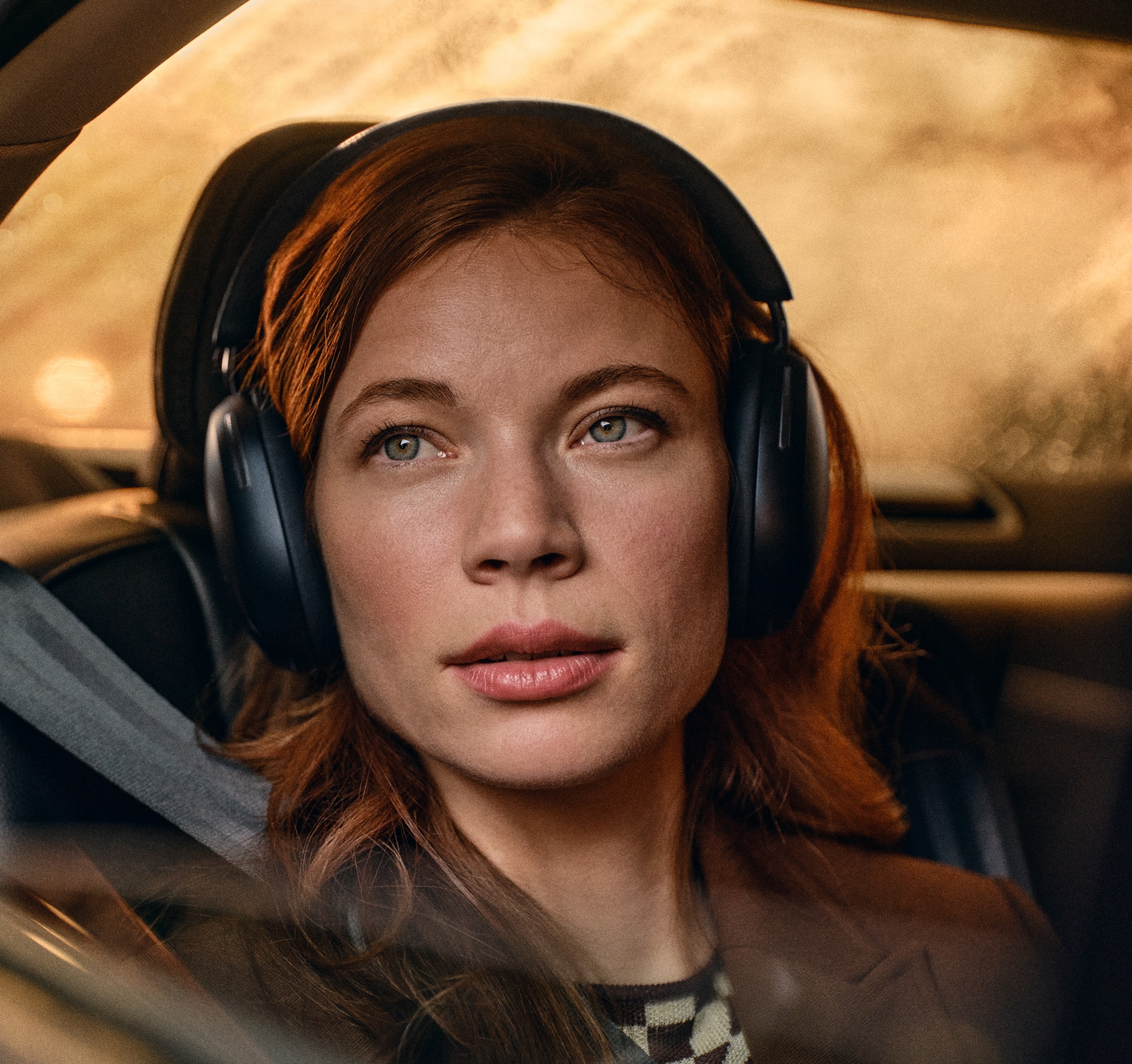 Una mujer lleva puesto un par de audífonos Sonos Ace en negro mientras viaja en un auto