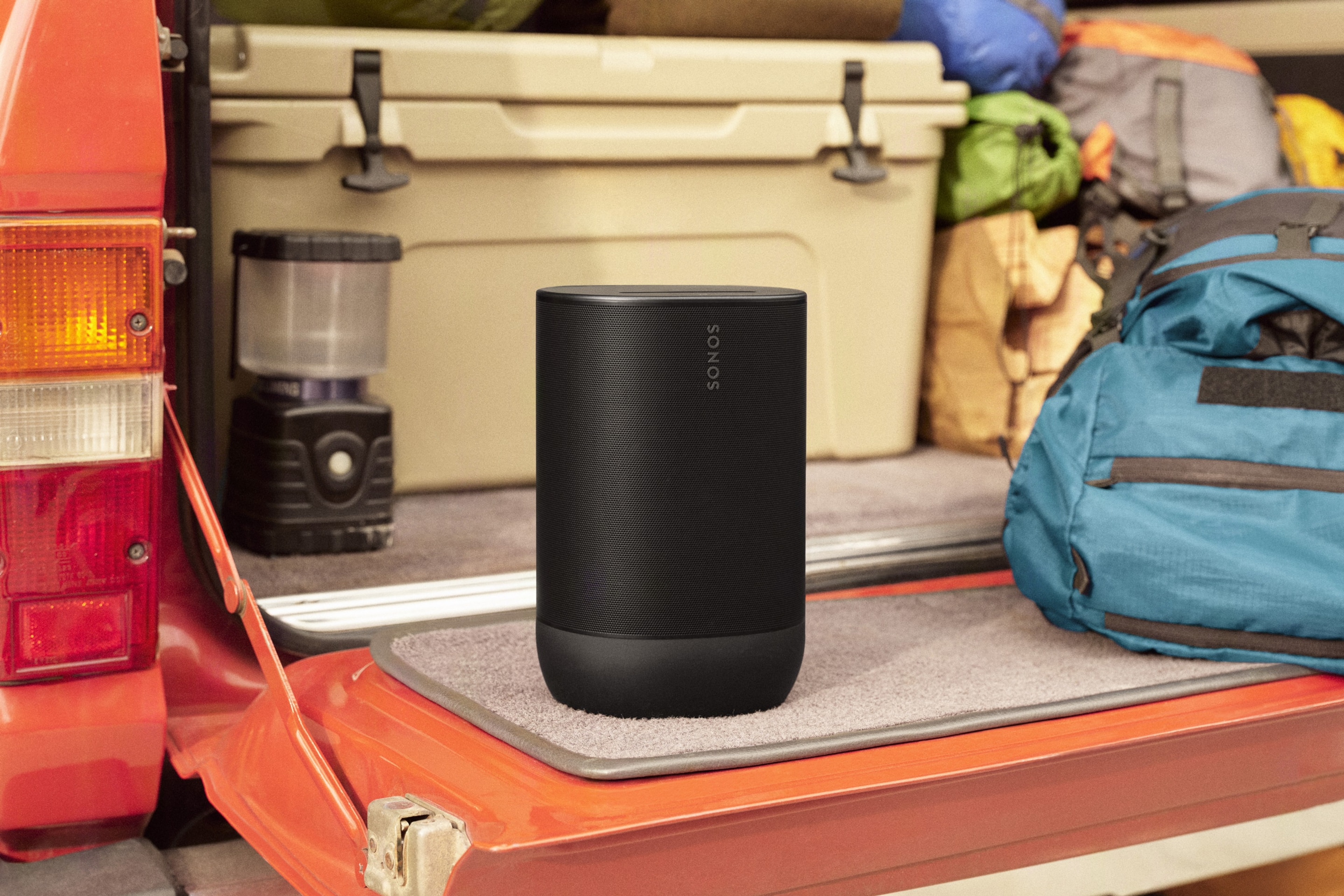 A black Sonos Move 2 on a truck tailgate with a cooler and a camping bag