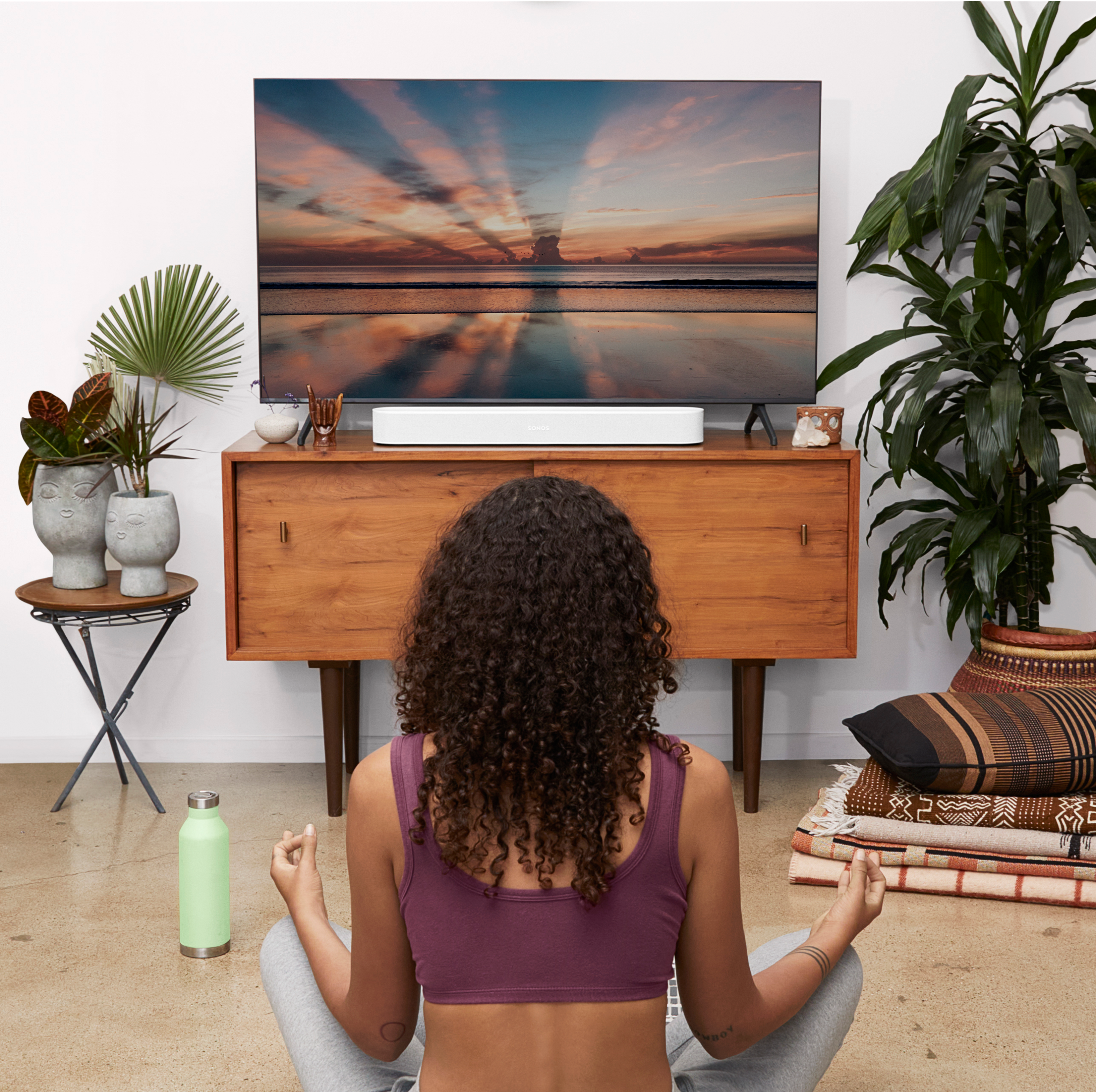 Woman sitting and meditating listening to Sonos Beam