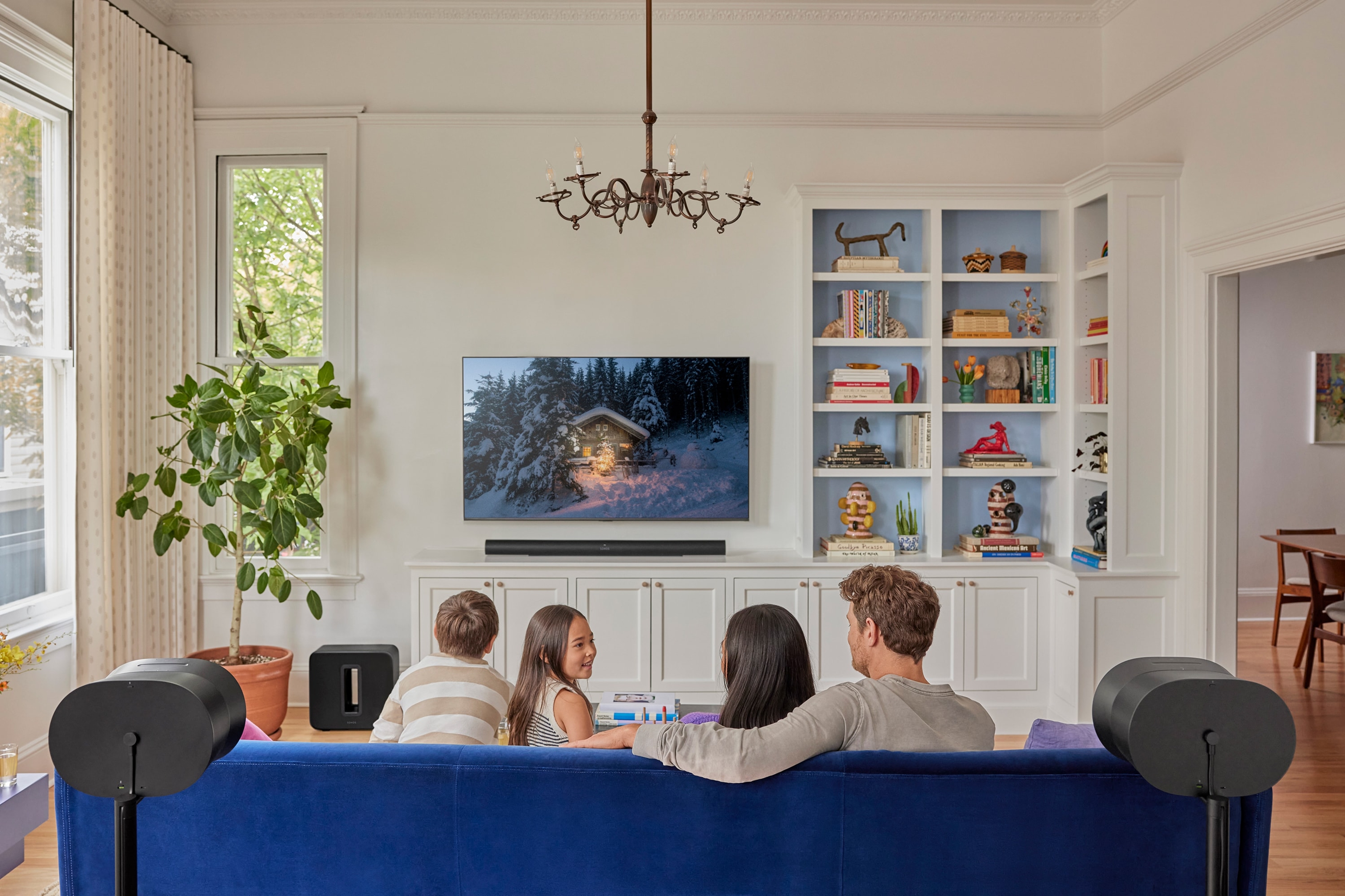 Family watching tv with a black Arc Ultra, Sub 4, and pair of Era 300