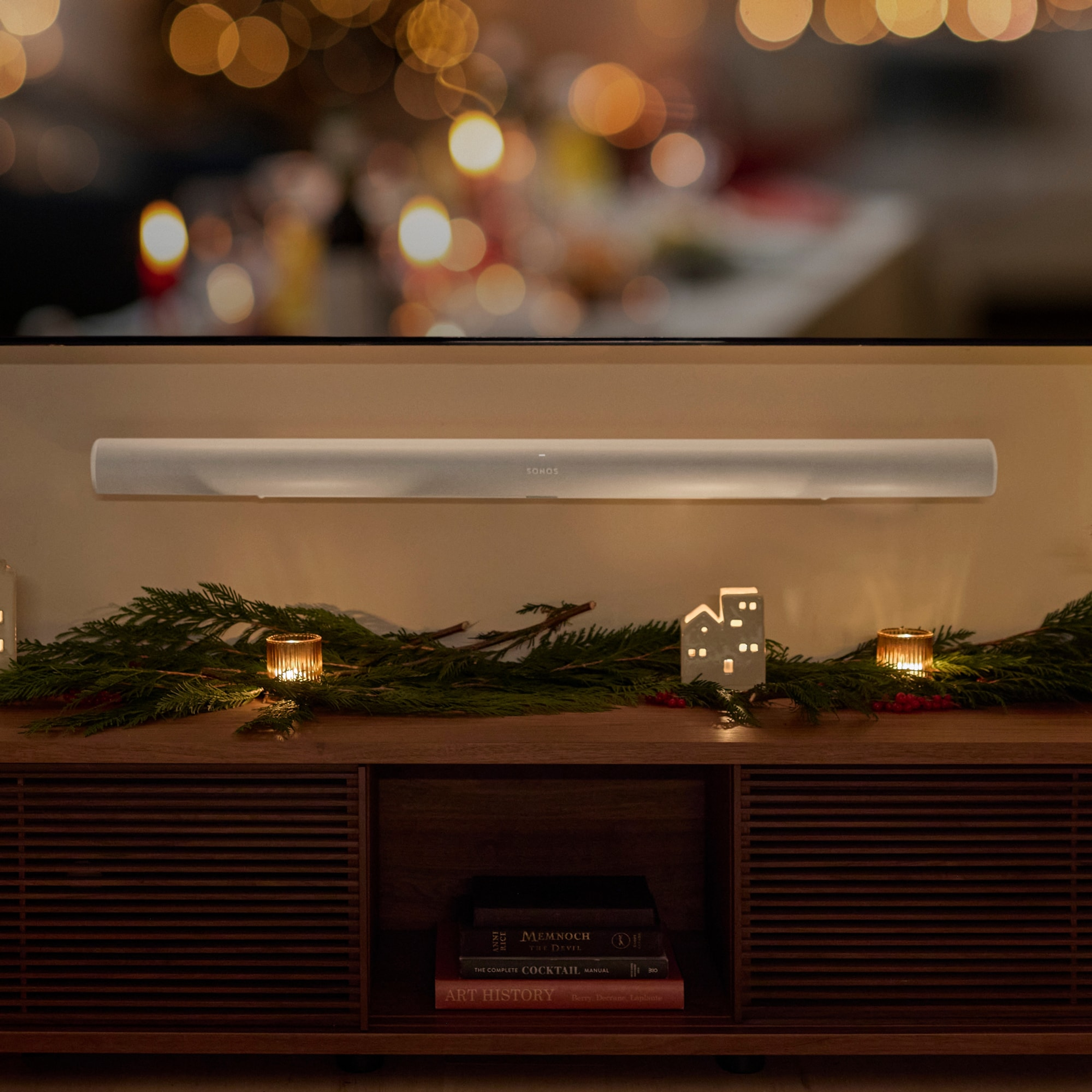 放在挂有节日花环的餐具柜上方的壁挂式白色Sonos Arc Ultra