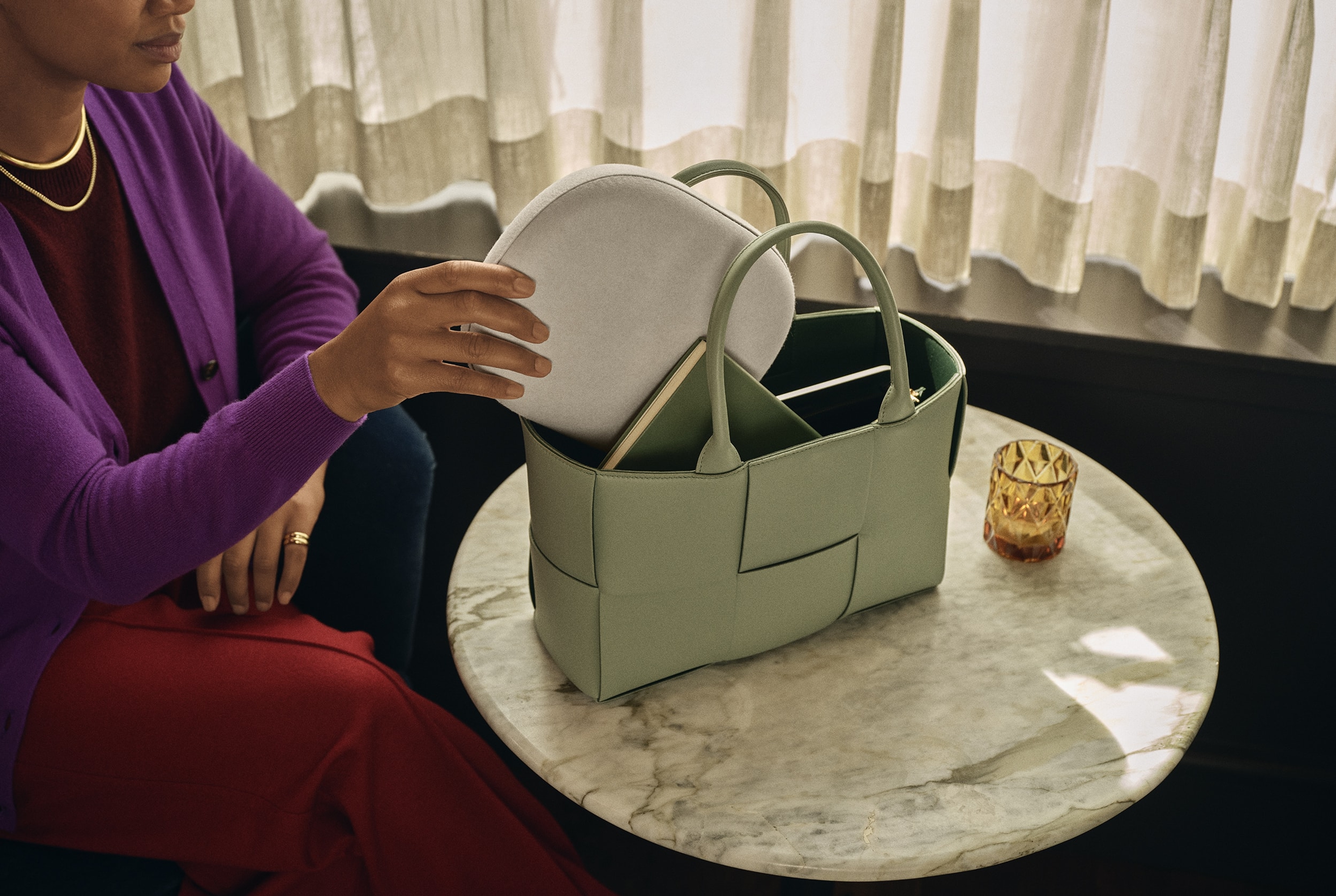 Person som stoppar en vit Sonos Ace-väska i en grön handväska