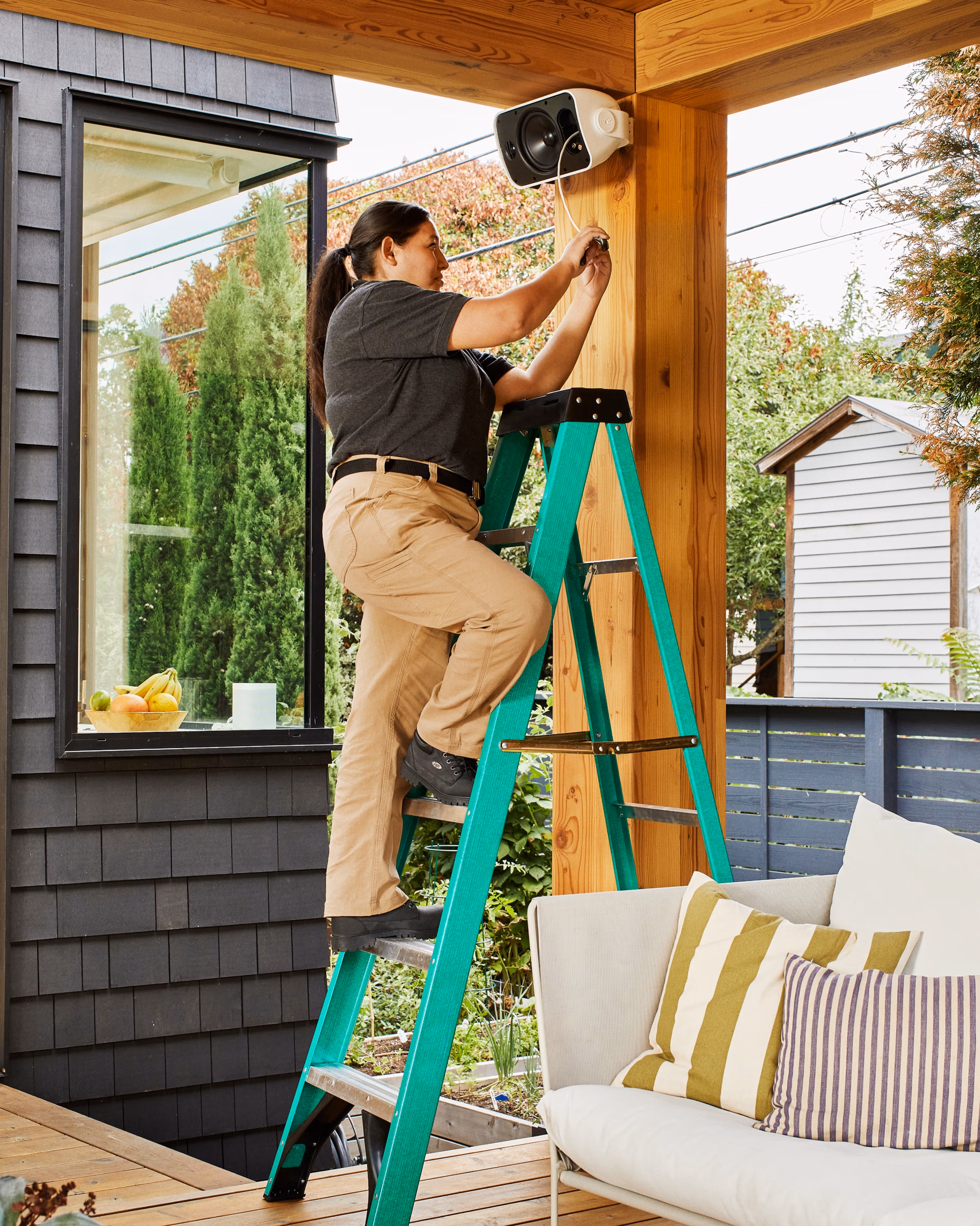 Installatör som monterar en utomhushögtalare från Sonos och Sonance på en altan