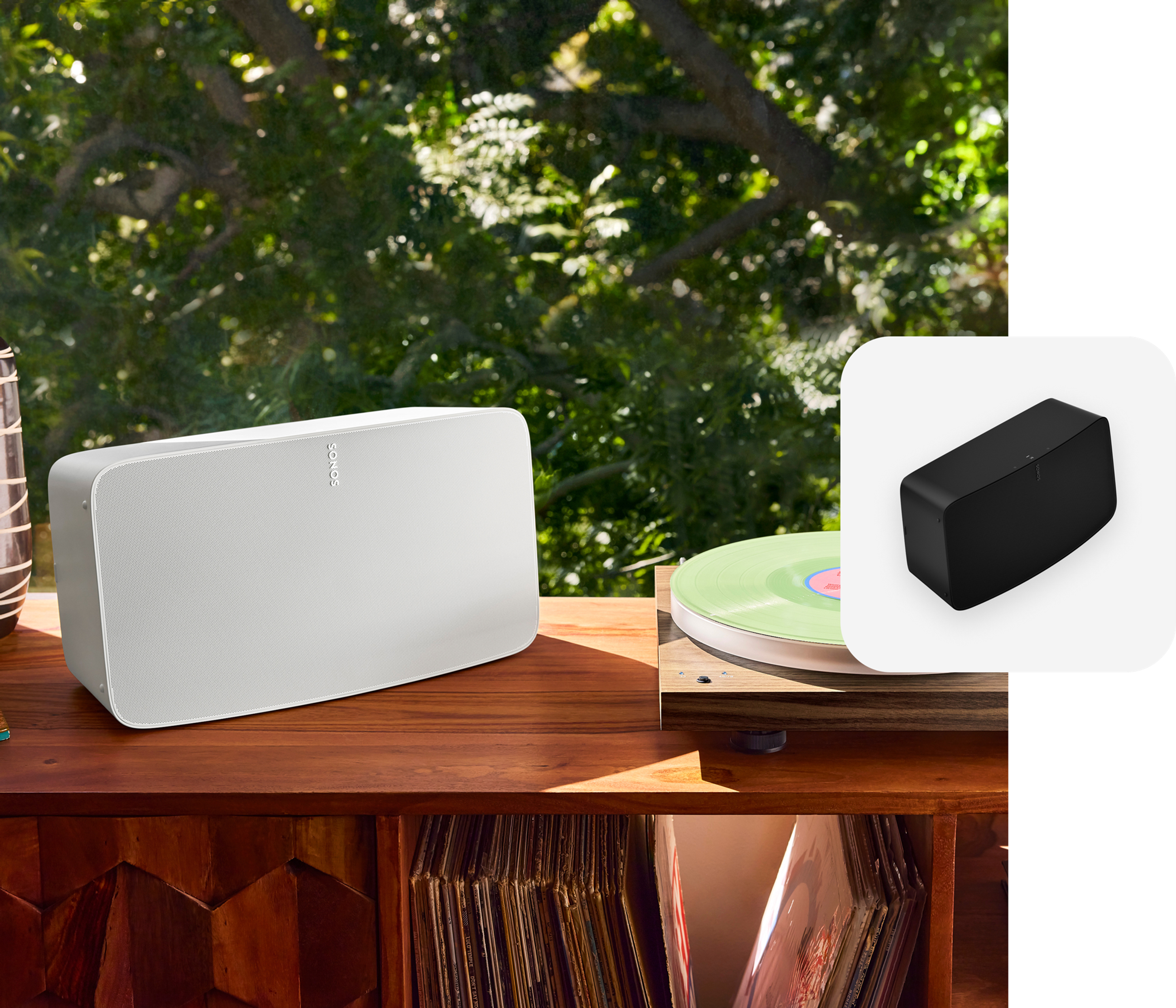 A white Sonos Five speaker next to a turntable on a record console