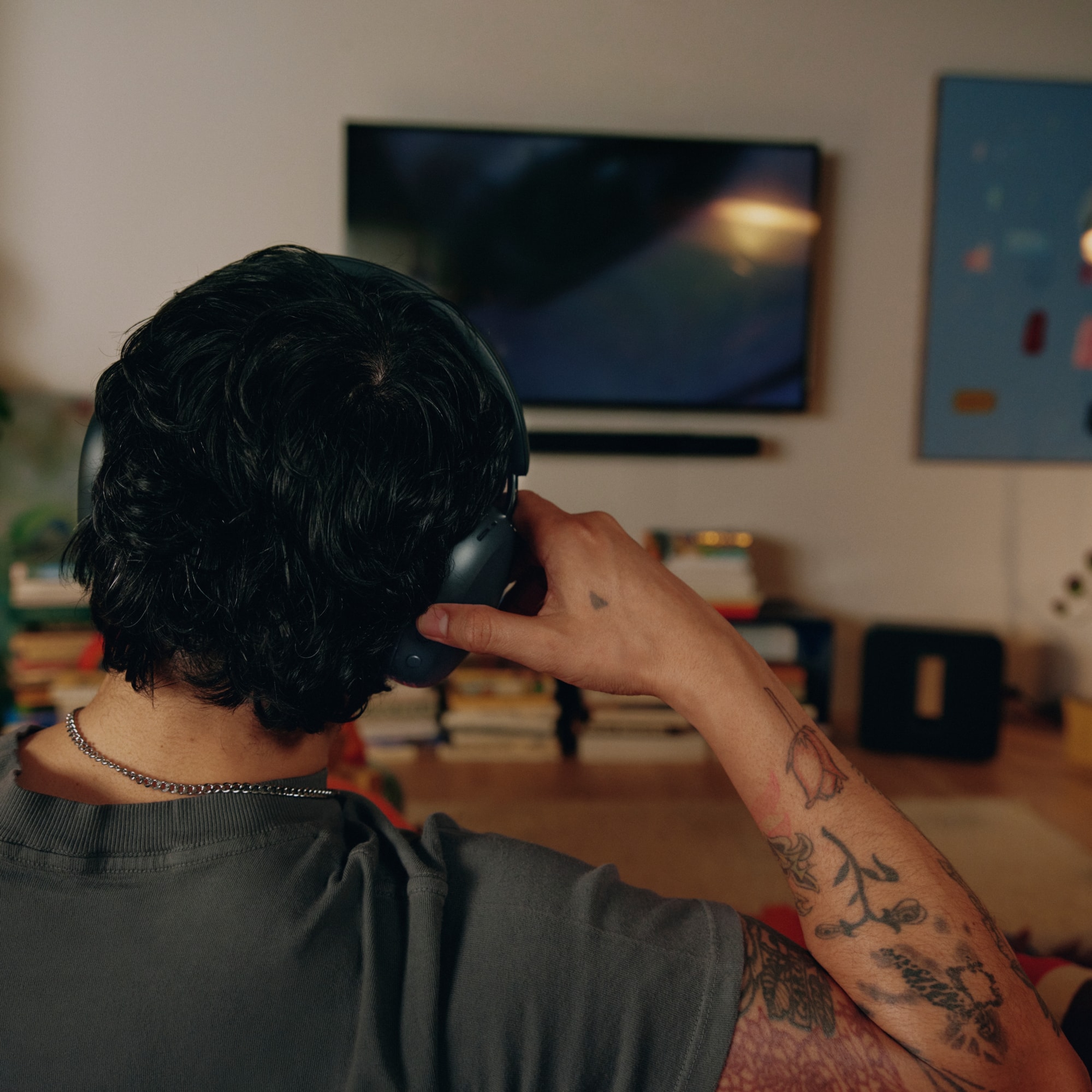 Person wearing black Sonos Ace Ultra headphones on the couch in a living room watching a movie