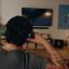 Person wearing black Sonos Ace Ultra headphones on the couch in a living room watching a film