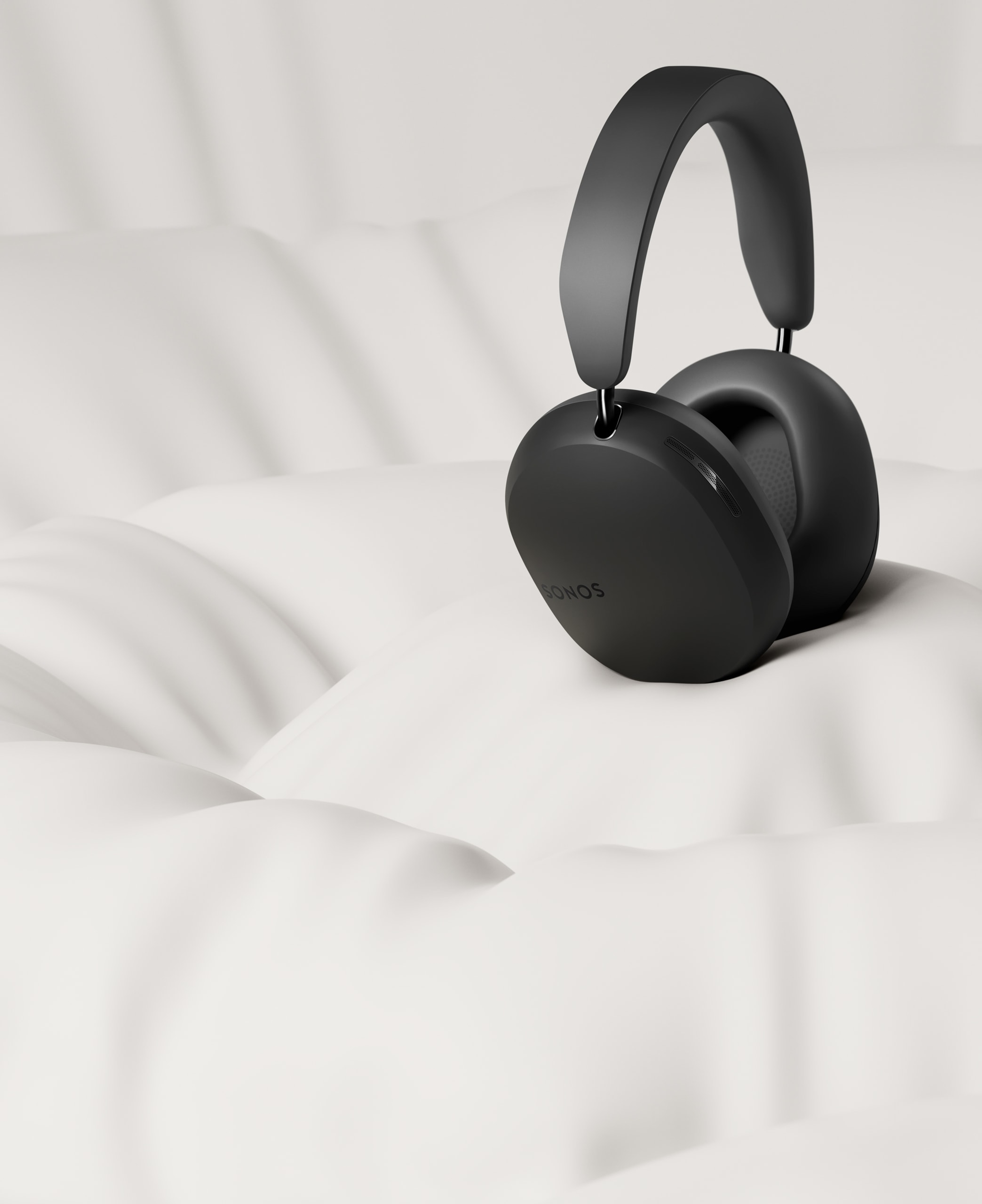 A pair of black Sonos Ace headphones on a pillowy white background