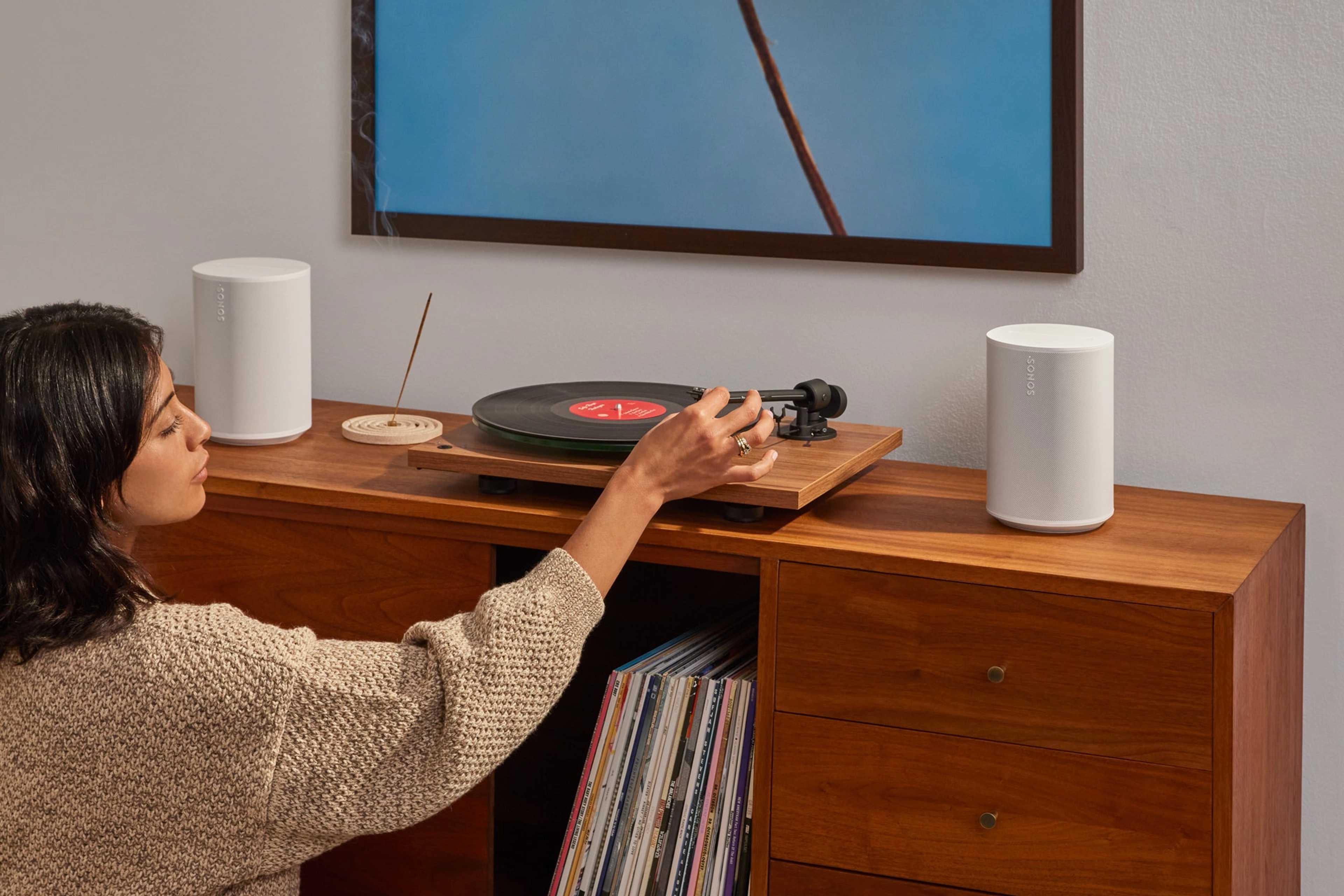 ターンテーブルに接続された2台のSonos Era 100 SLスピーカー(ホワイト)でアナログ盤レコードを聴くユーザー