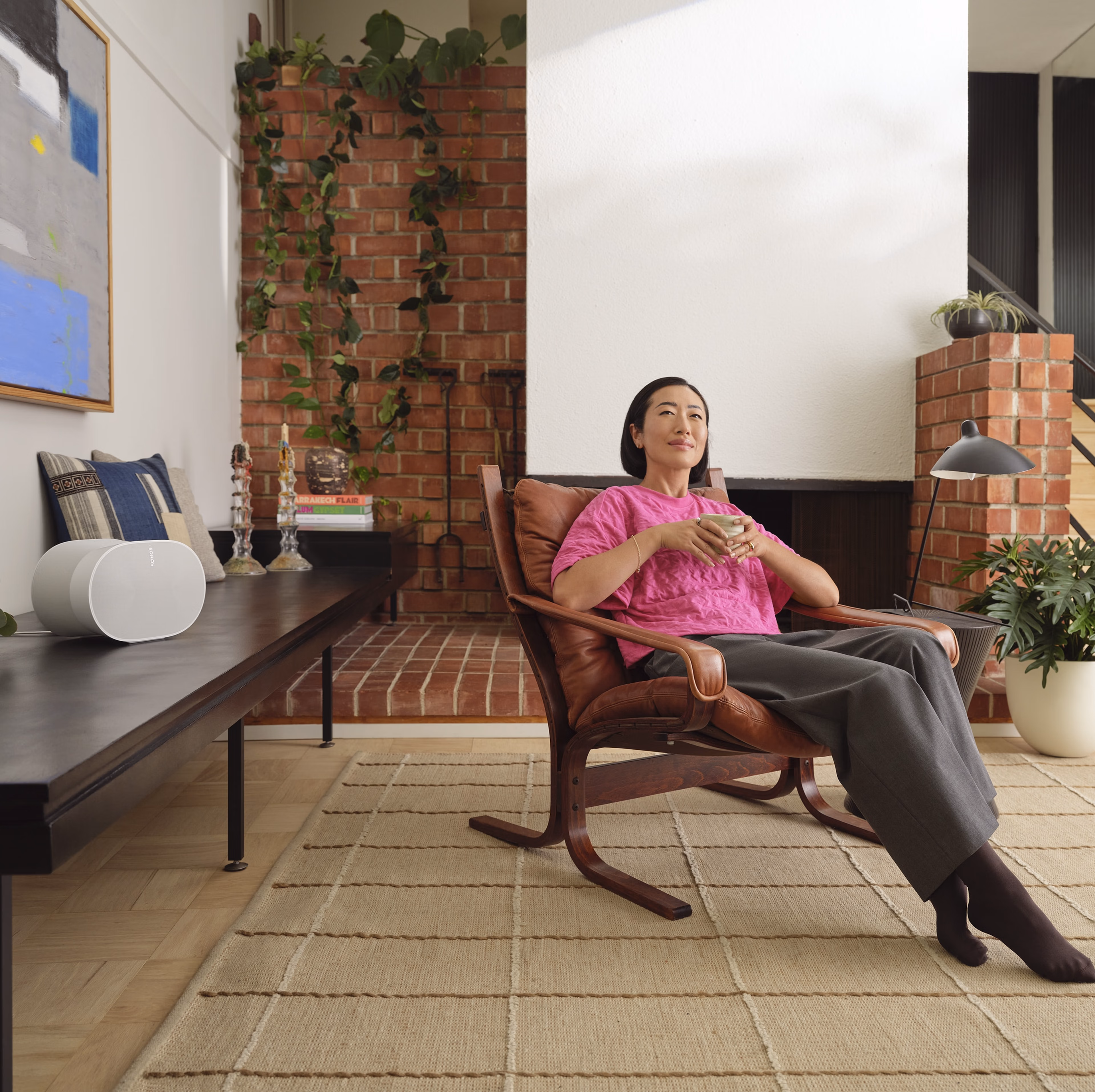 Woman seated in her living room listening to a white Era 300 speaker