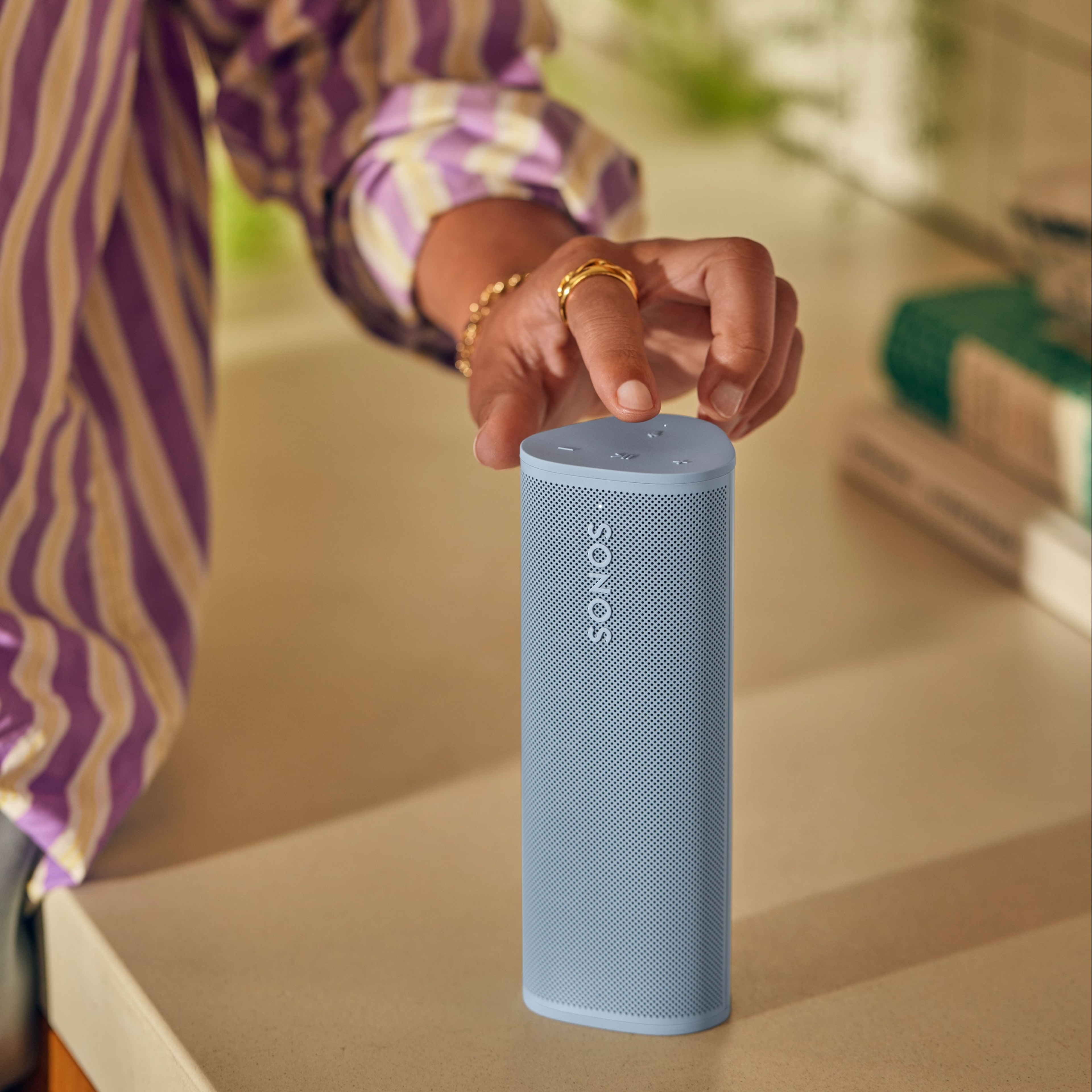 Closeup view of a hand tapping Sonos Roam 2 in Wave
