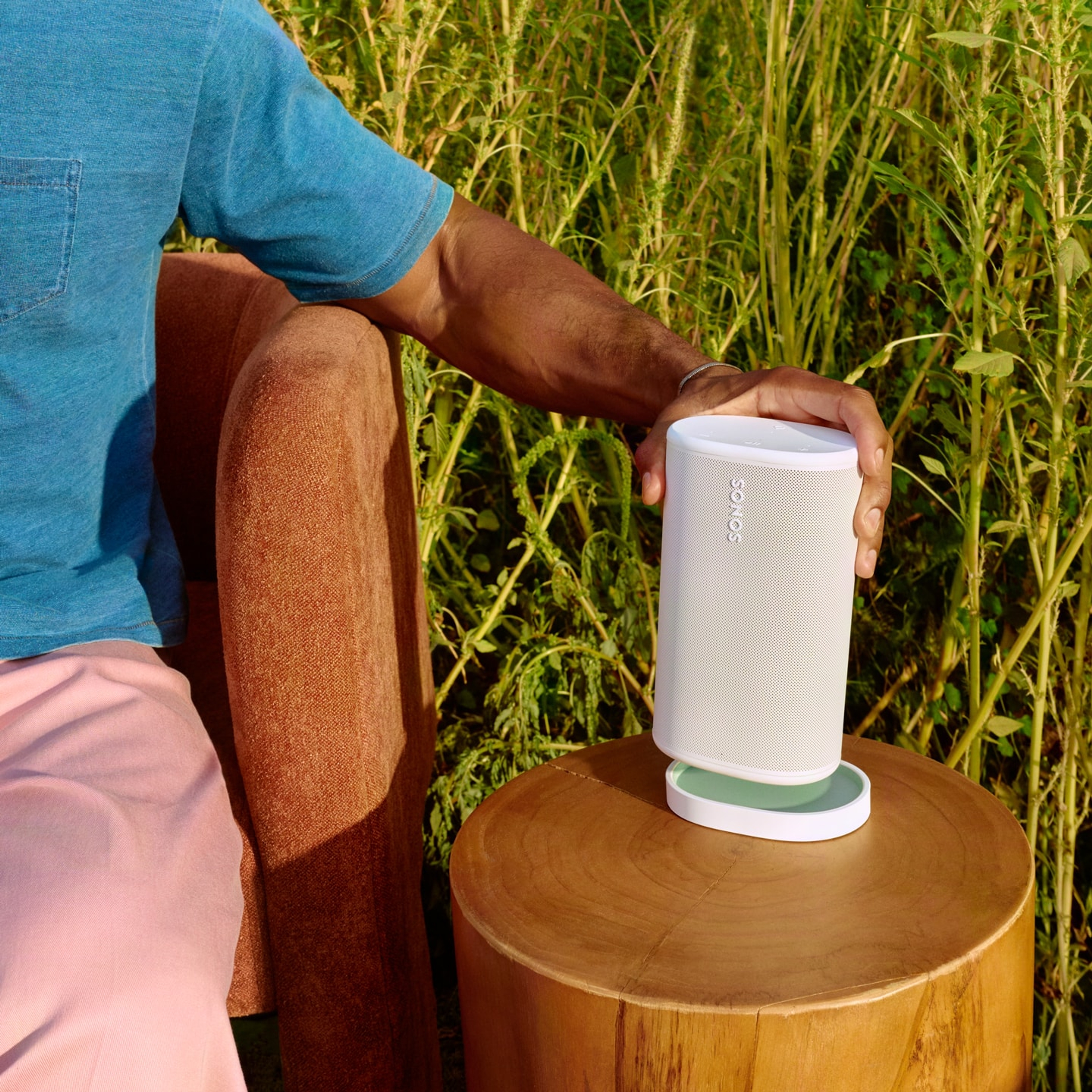 Utilizator așezând o boxă Sonos Play albă în baza de încărcare asortată