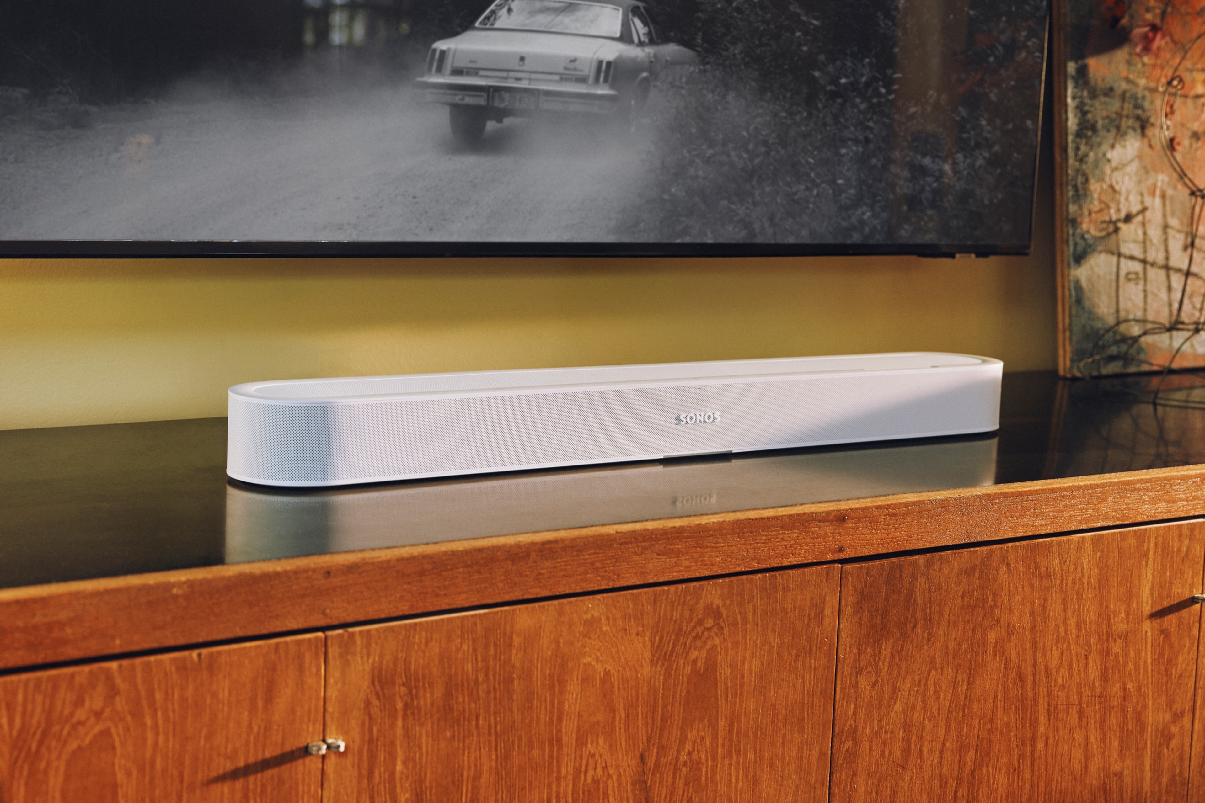 A white Sonos Beam Ultra soundbar on wooden TV stand