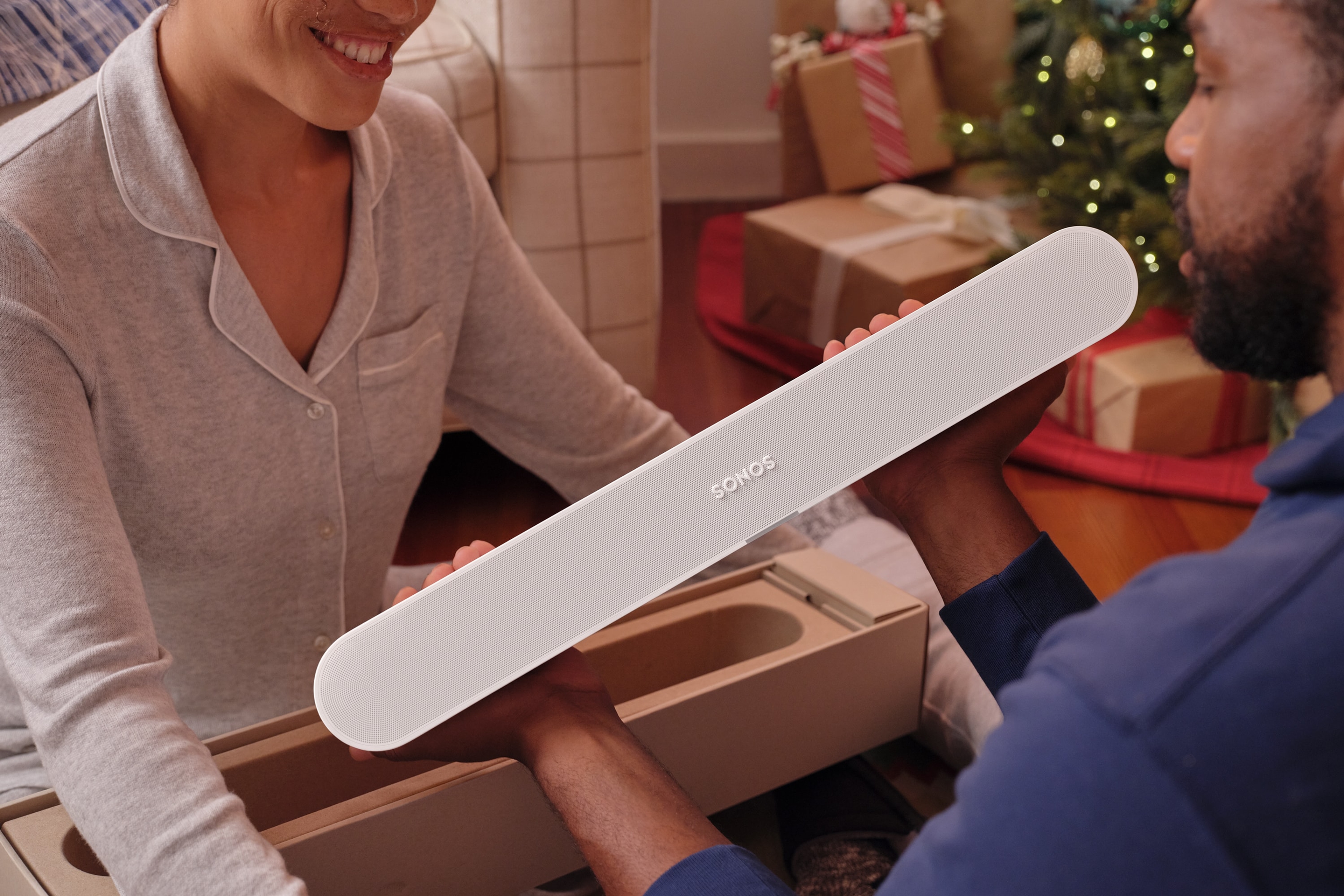 Two people unboxing a white Sonos Ray